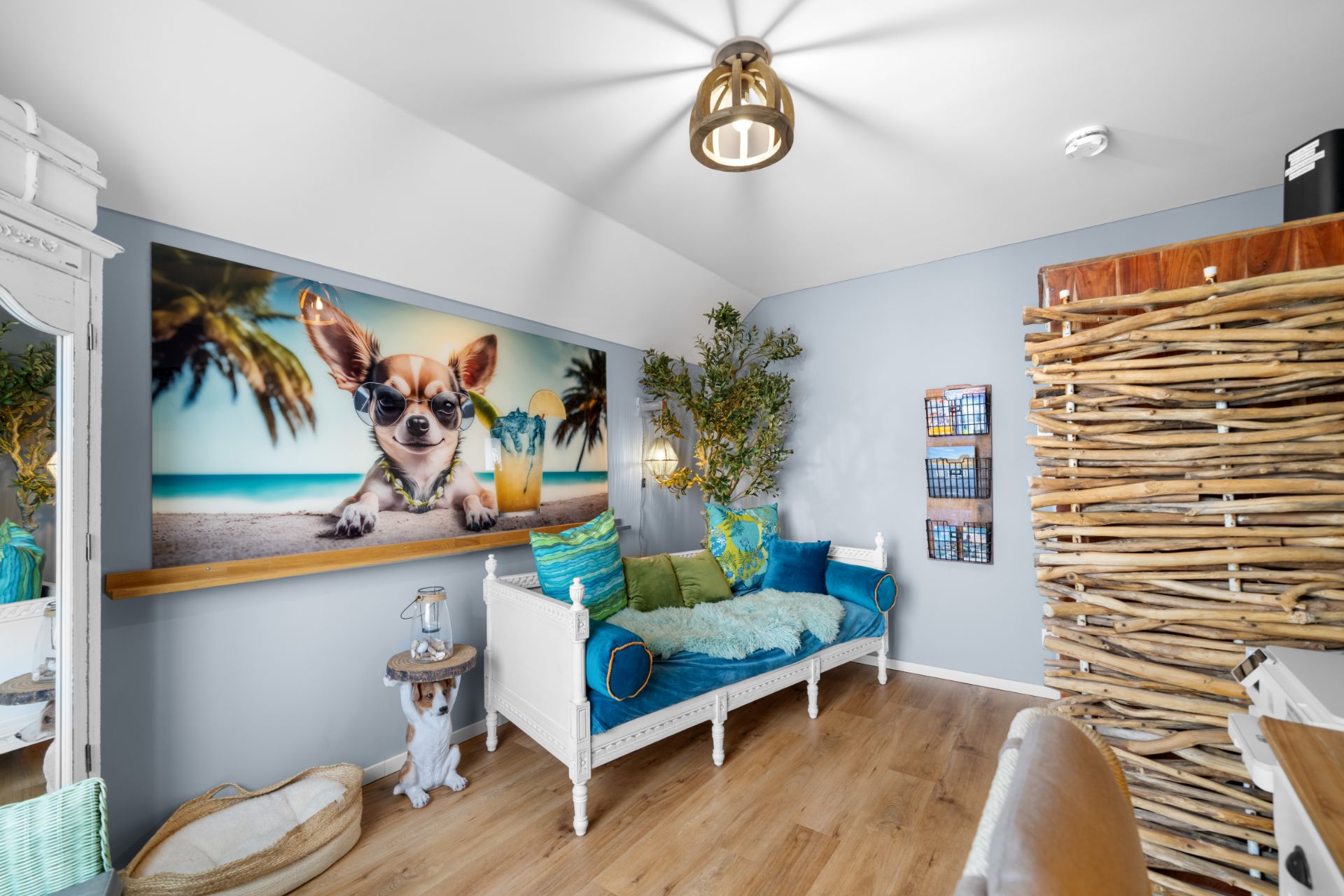 Helles Wohnzimmer mit Sofa, bunten Kissen, Wandbild eines Hundes und Holzfußboden.