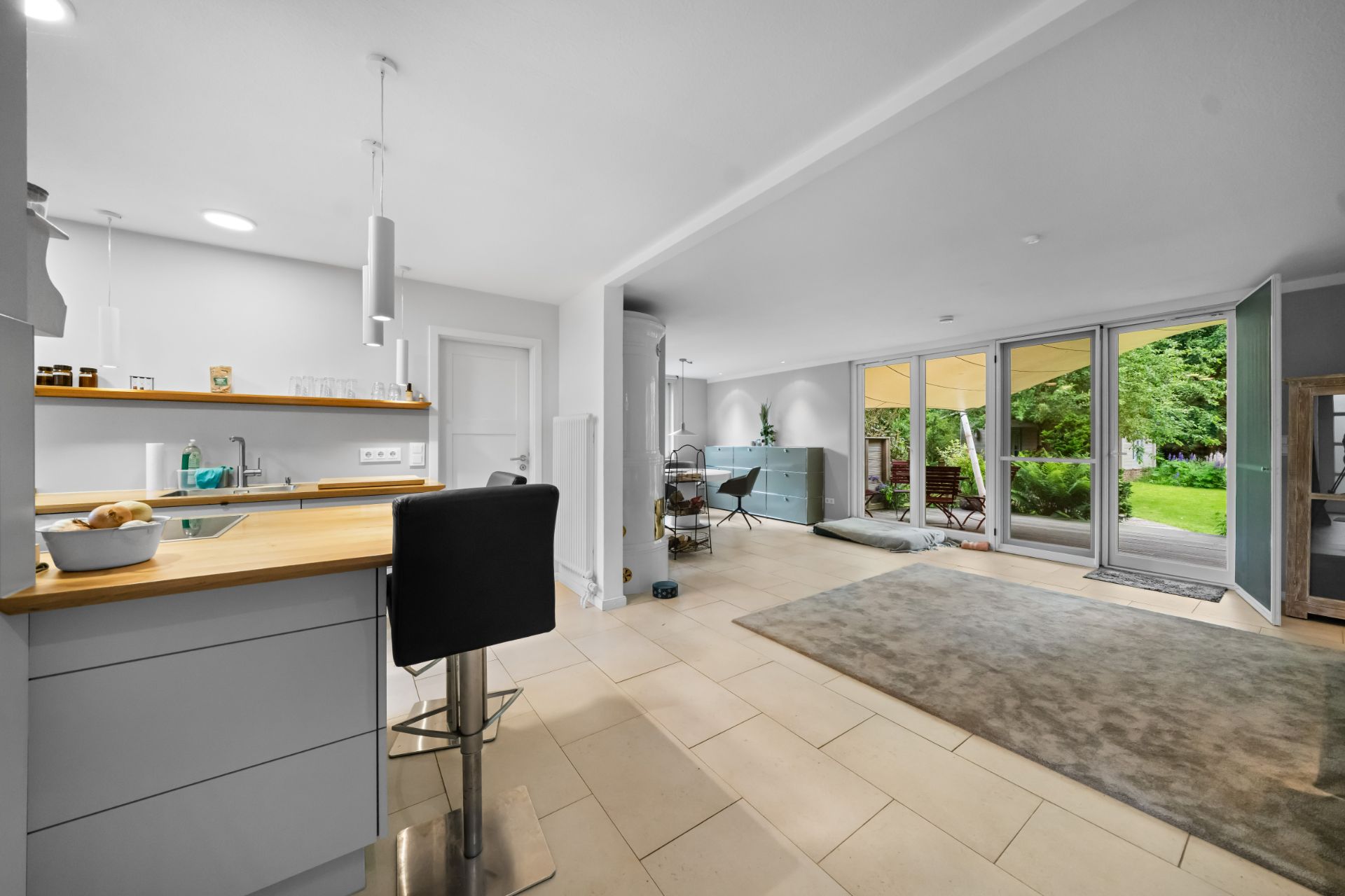 Offene Küche und Wohnzimmer mit großen Fenstern und Blick in den Garten.