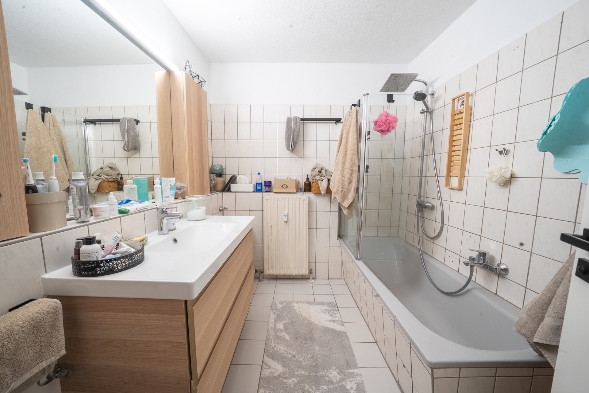 Modernes Badezimmer mit Badewanne, Waschbecken, Spiegel und Handtüchern.