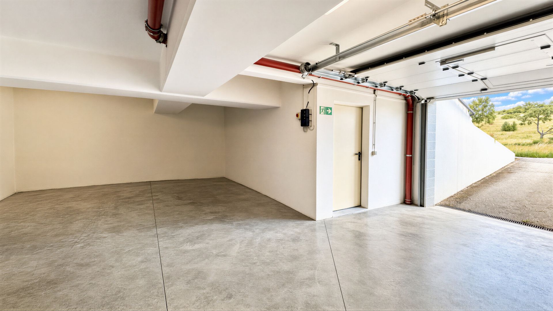 Helle, leere Garage mit offenem Tor und Tür an der Seitenwand.