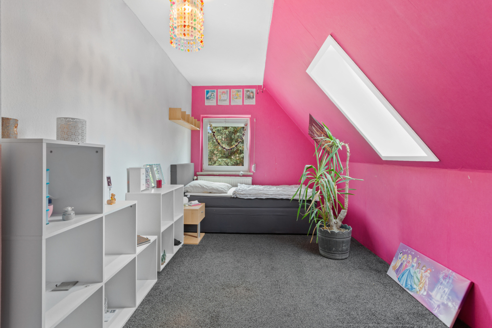 Modernes Kinderzimmer mit pinker Wand, Einzelbett, Regal, Pflanze und schrägem Dachfenster.