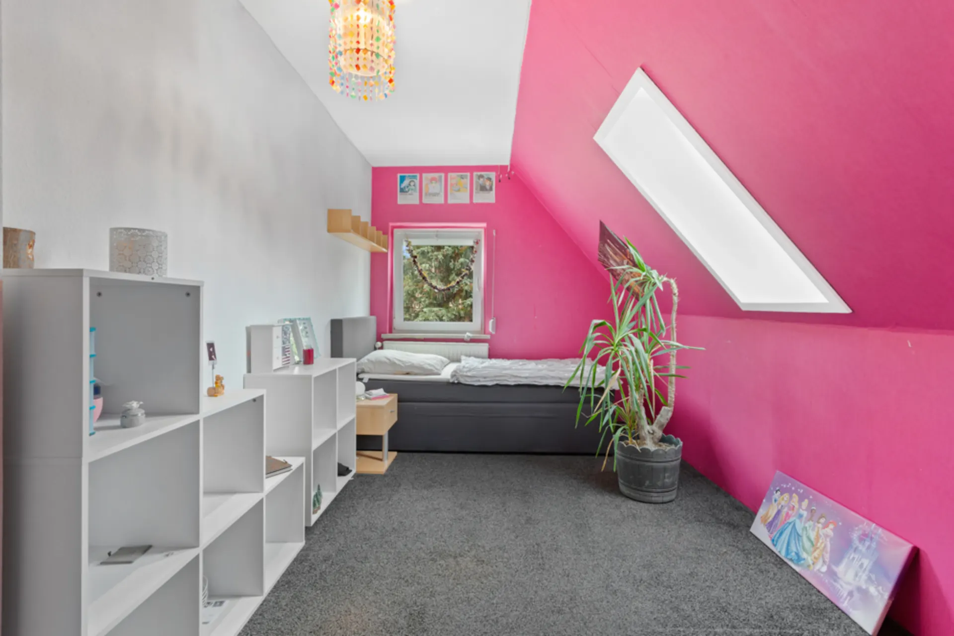 Modernes Kinderzimmer mit pinker Wand, Einzelbett, Regal, Pflanze und schrägem Dachfenster.