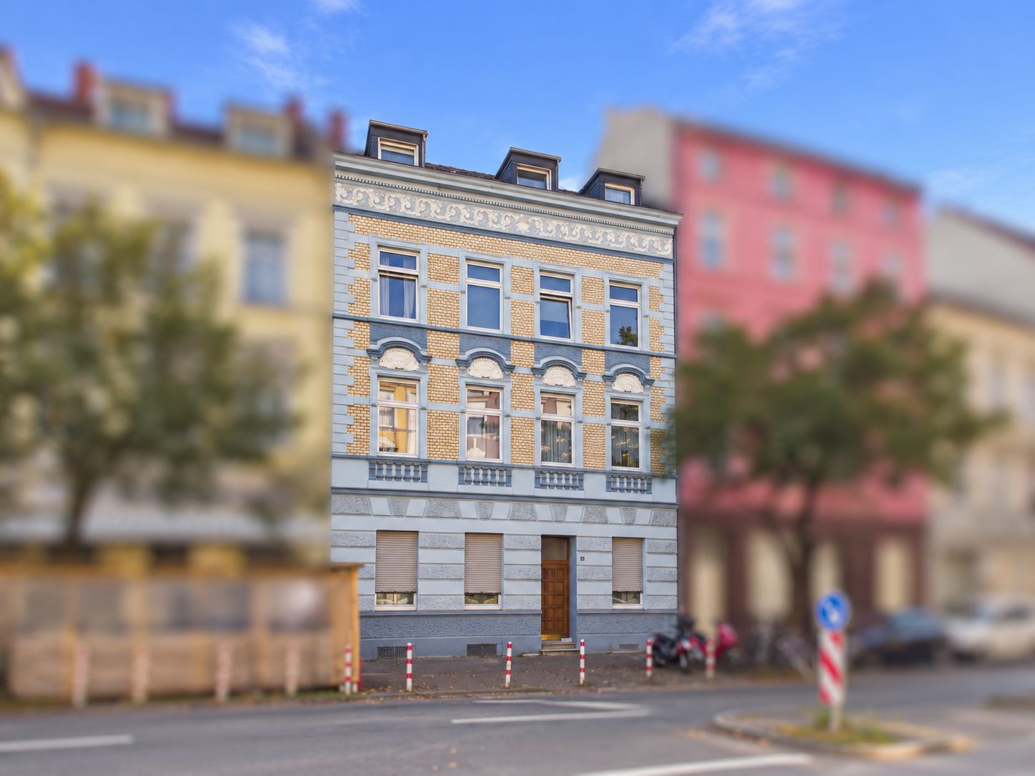 Dreistöckiges Wohngebäude mit heller Fassade und mehreren Fenstern an einer Straße.