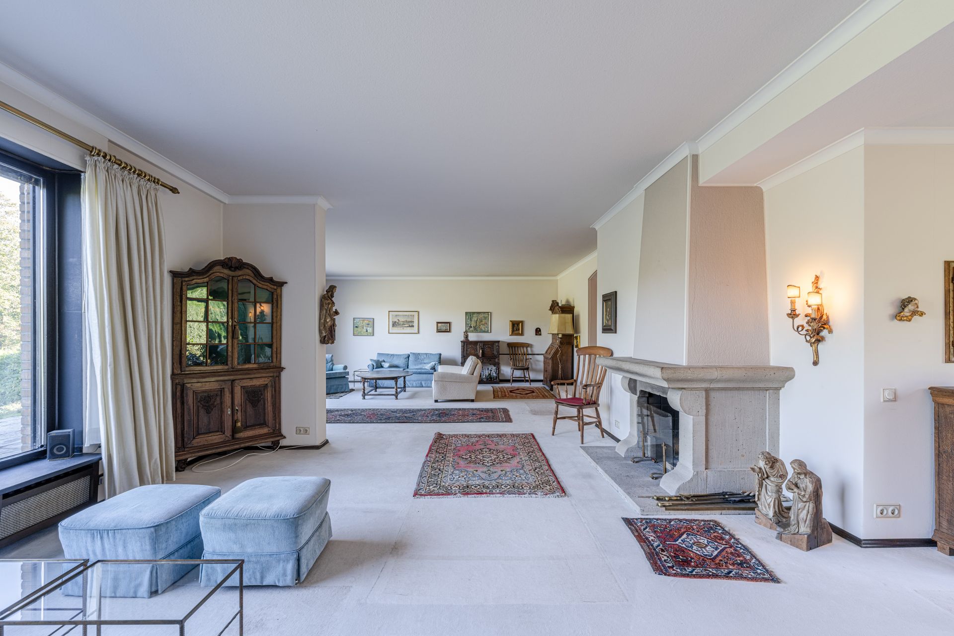 Großes Wohnzimmer mit hellen Teppichen, Kamin, Holzmöbeln und mehreren Sofas.