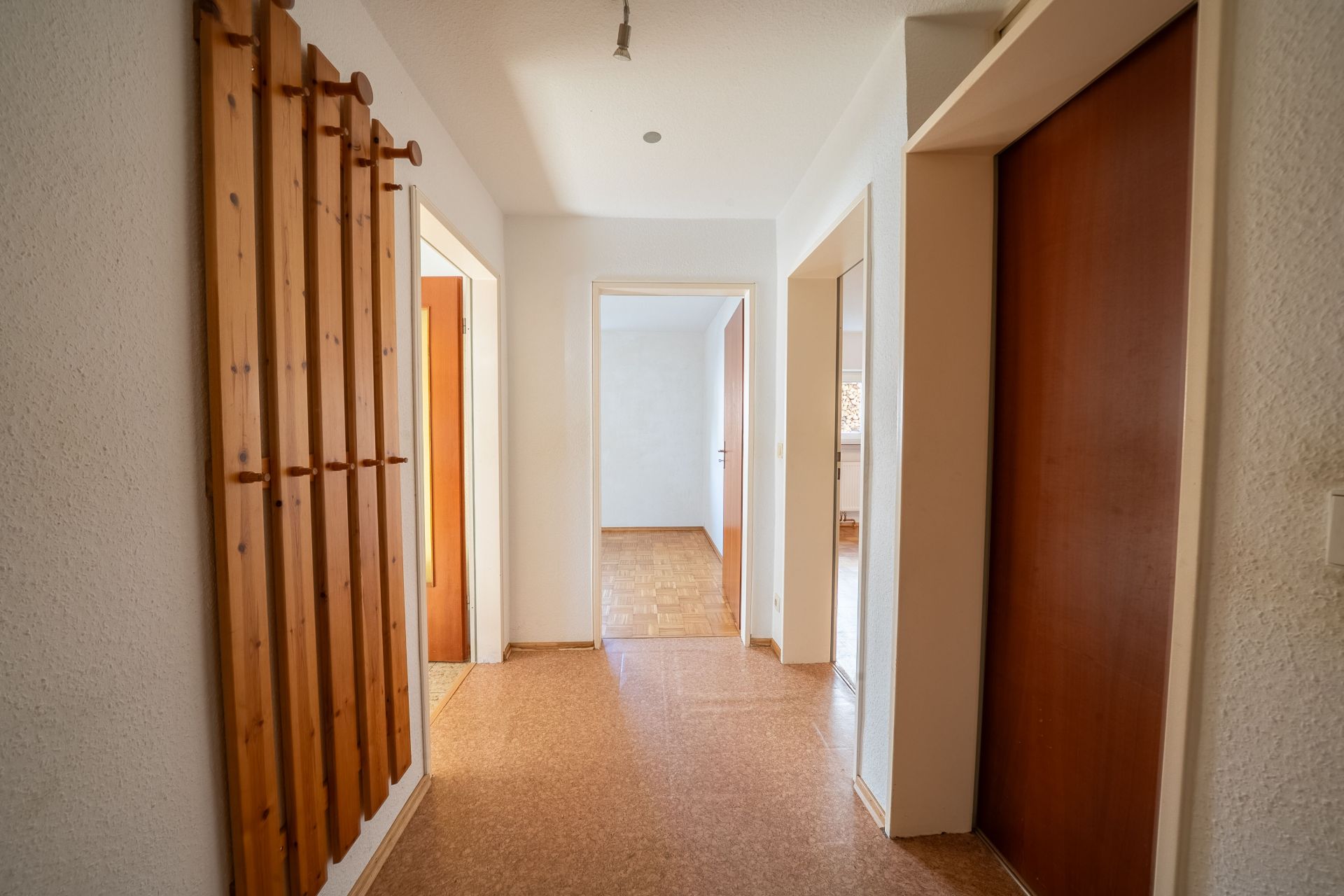 Heller Flur mit Holzgarderobe und mehreren Türen zu anderen Räumen.