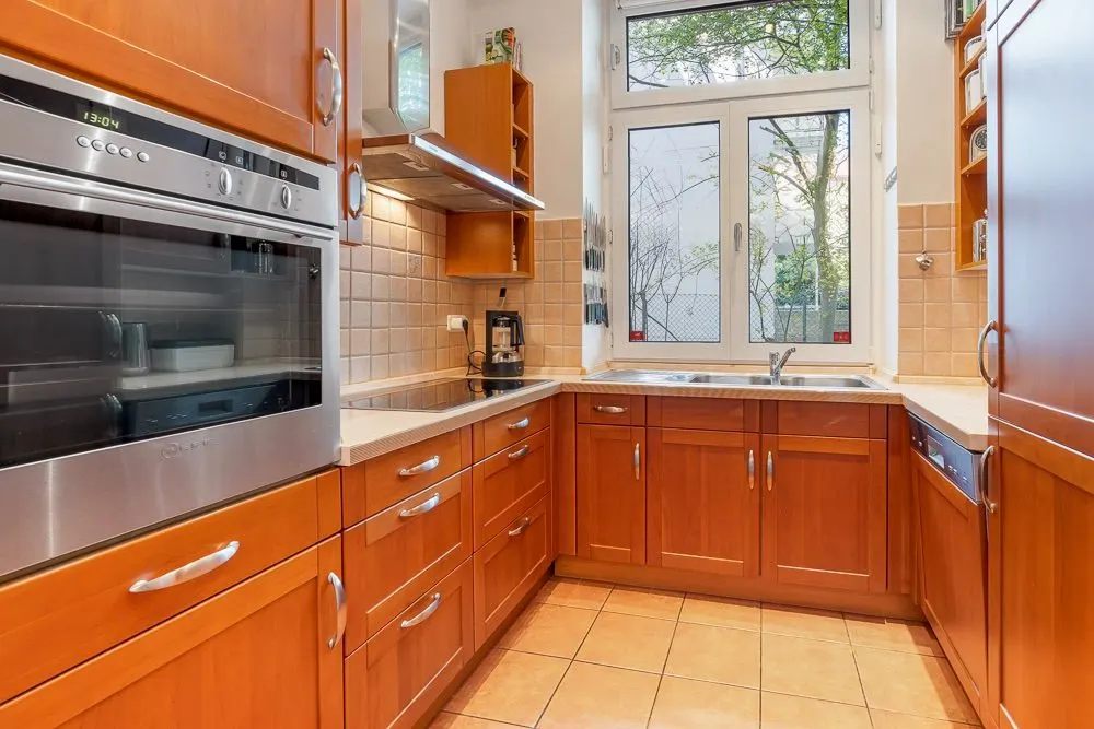 Moderne Küche mit Holzschränken, großem Fenster, Spüle und Einbaugeräten.