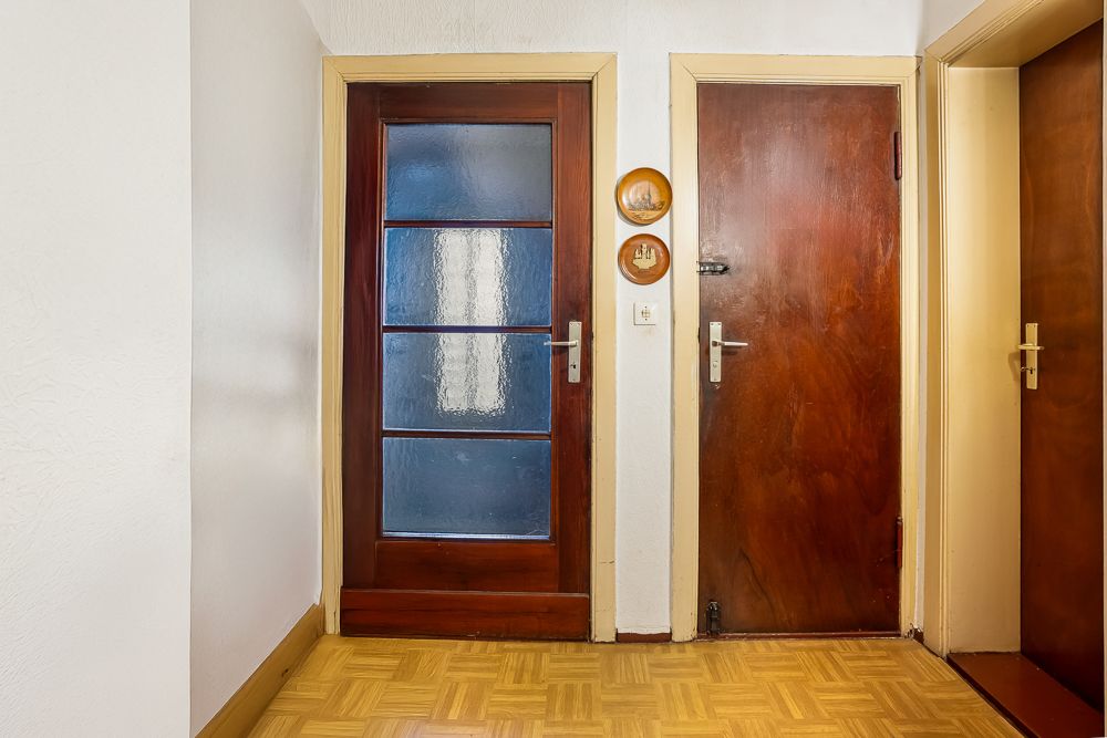 Flur mit drei Holztüren, Parkettboden und zwei runden Wanddekorationen.