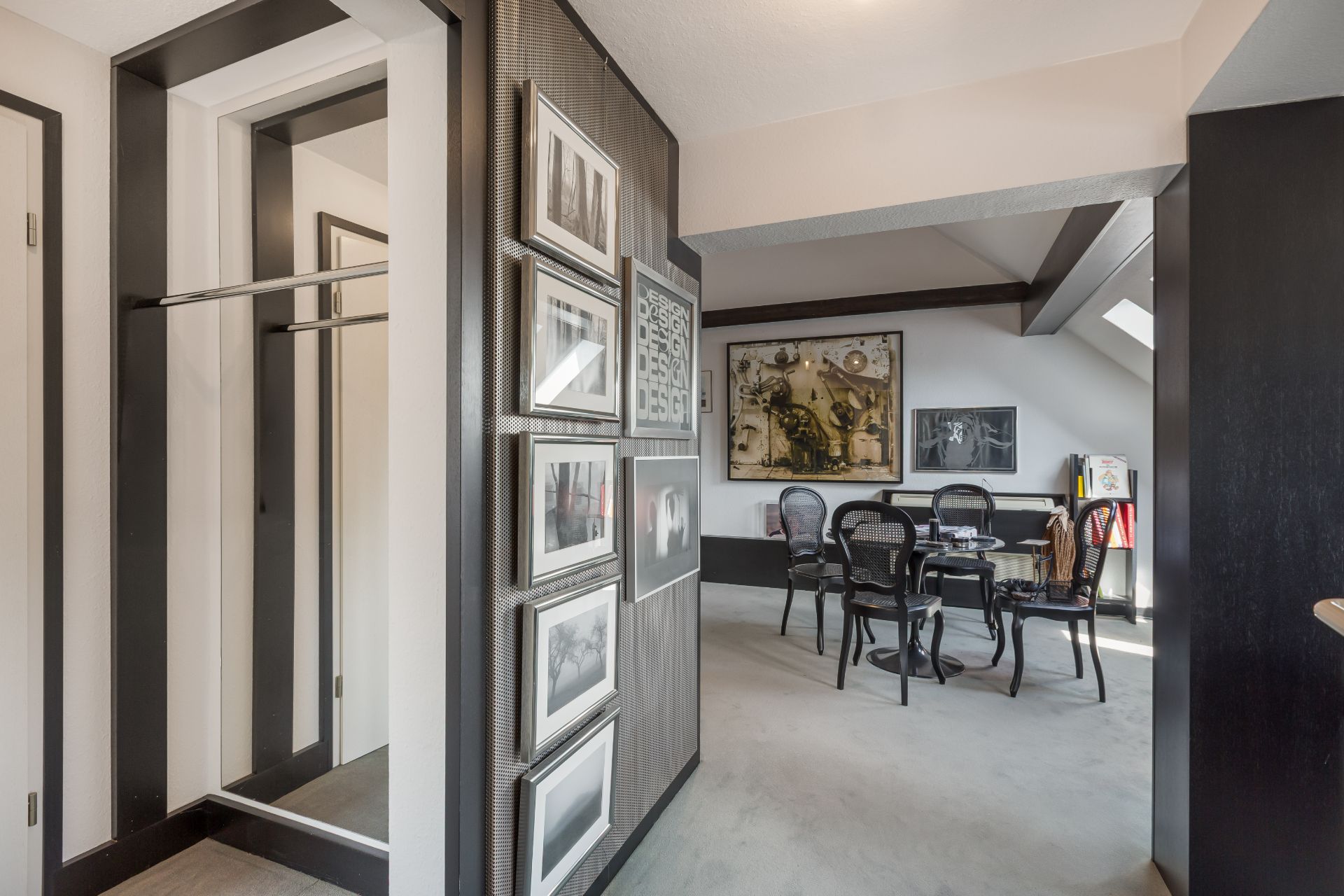 Flur mit Garderobe, Wandbildern und Essbereich mit vier Stühlen im Hintergrund.