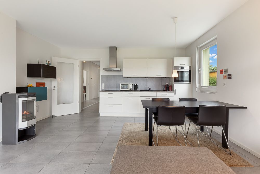 Moderne Küche mit Esstisch und vier Stühlen, Fenster rechts, Kamin links.