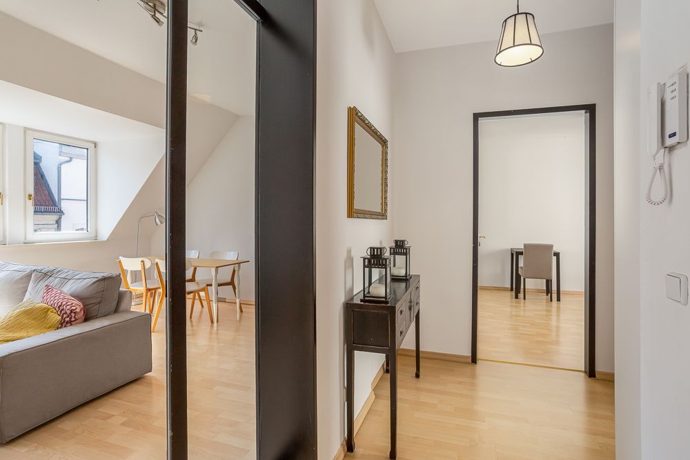 Heller Flur mit Konsole, Spiegel, Blick ins Wohnzimmer mit Sofa und Esstisch.