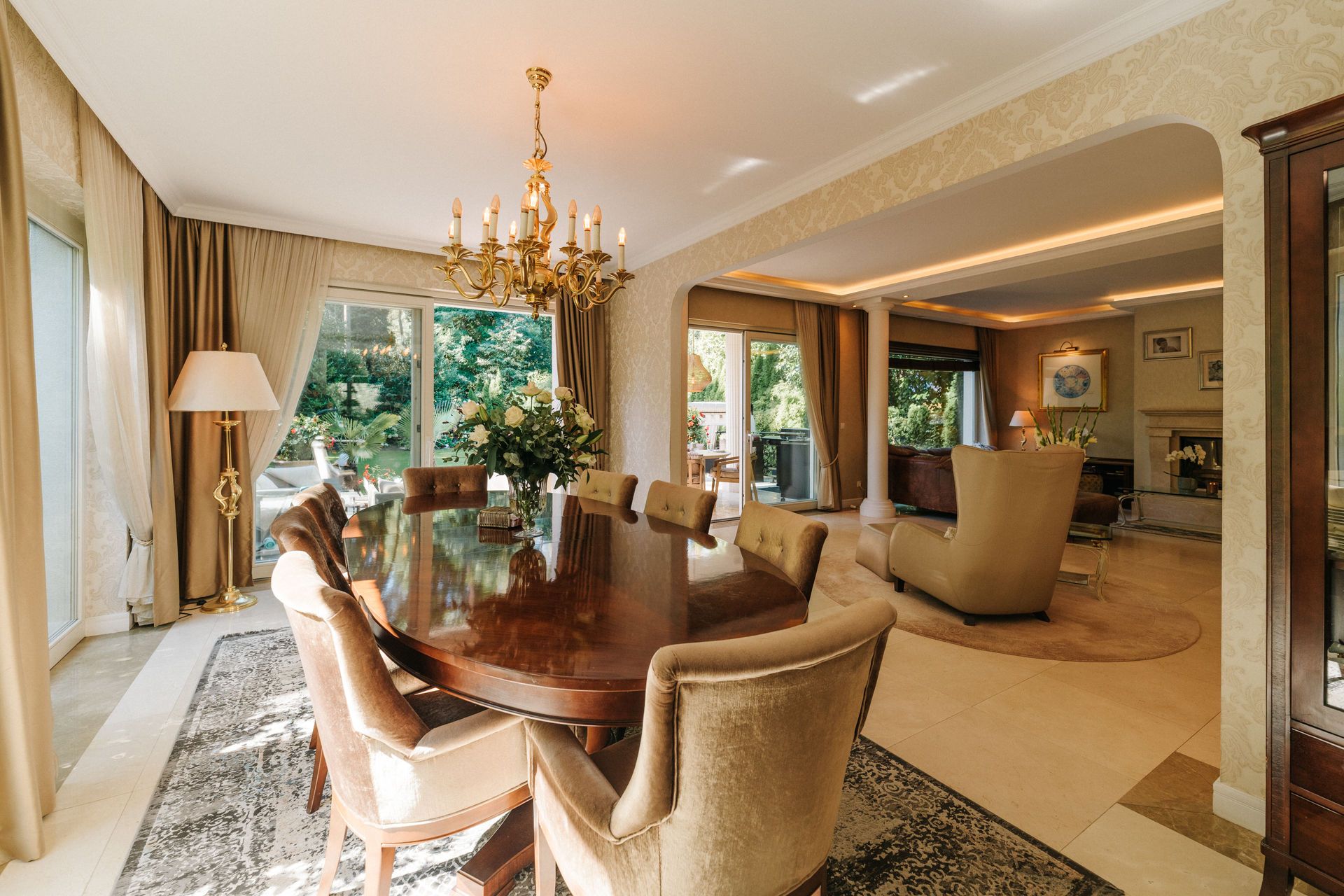 Elegantes Esszimmer mit großem Holztisch, gepolsterten Stühlen und Blick ins helle Wohnzimmer.