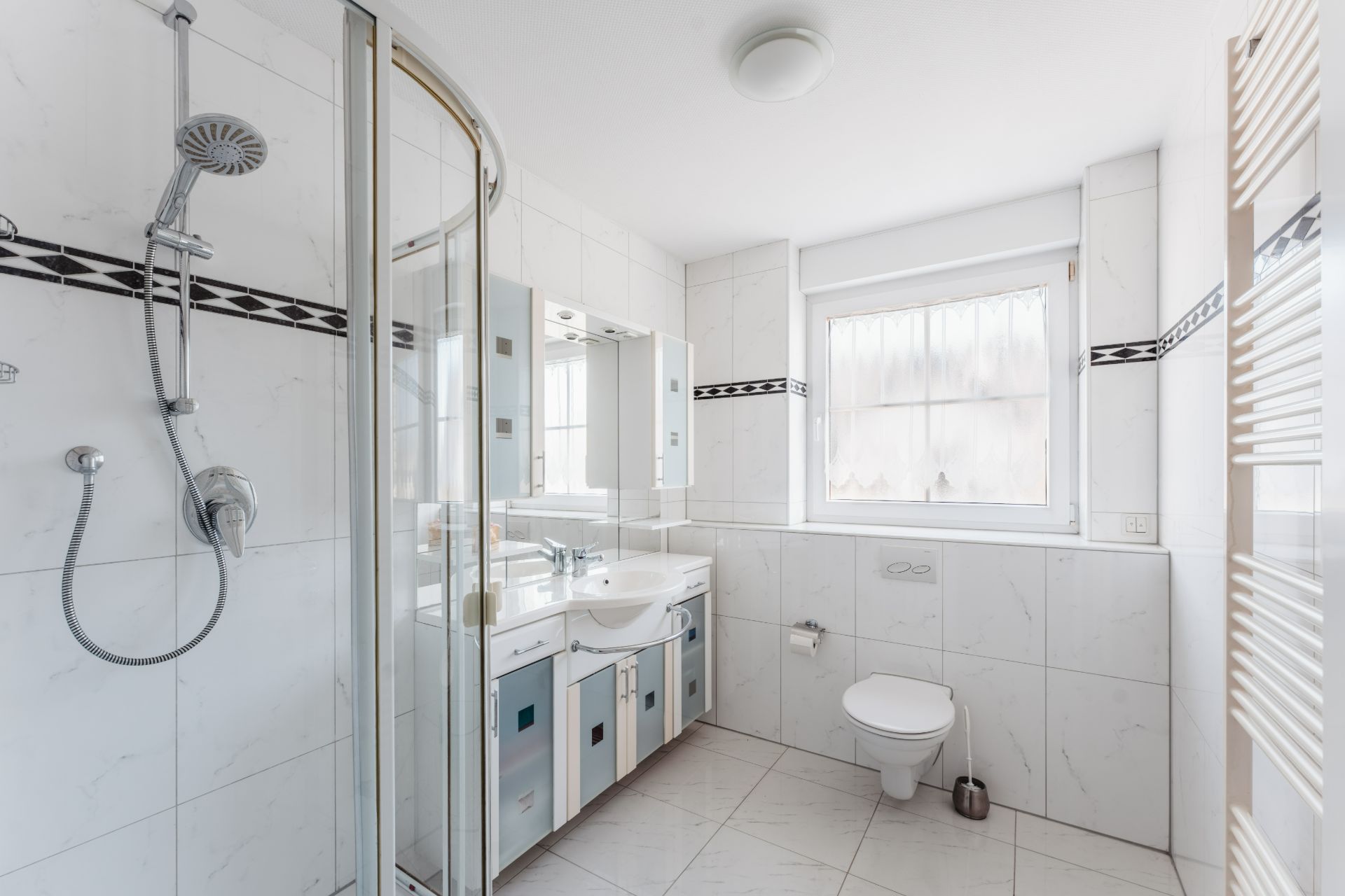 Helles Badezimmer mit Dusche, WC, Waschbecken, Spiegel und Fenster.
