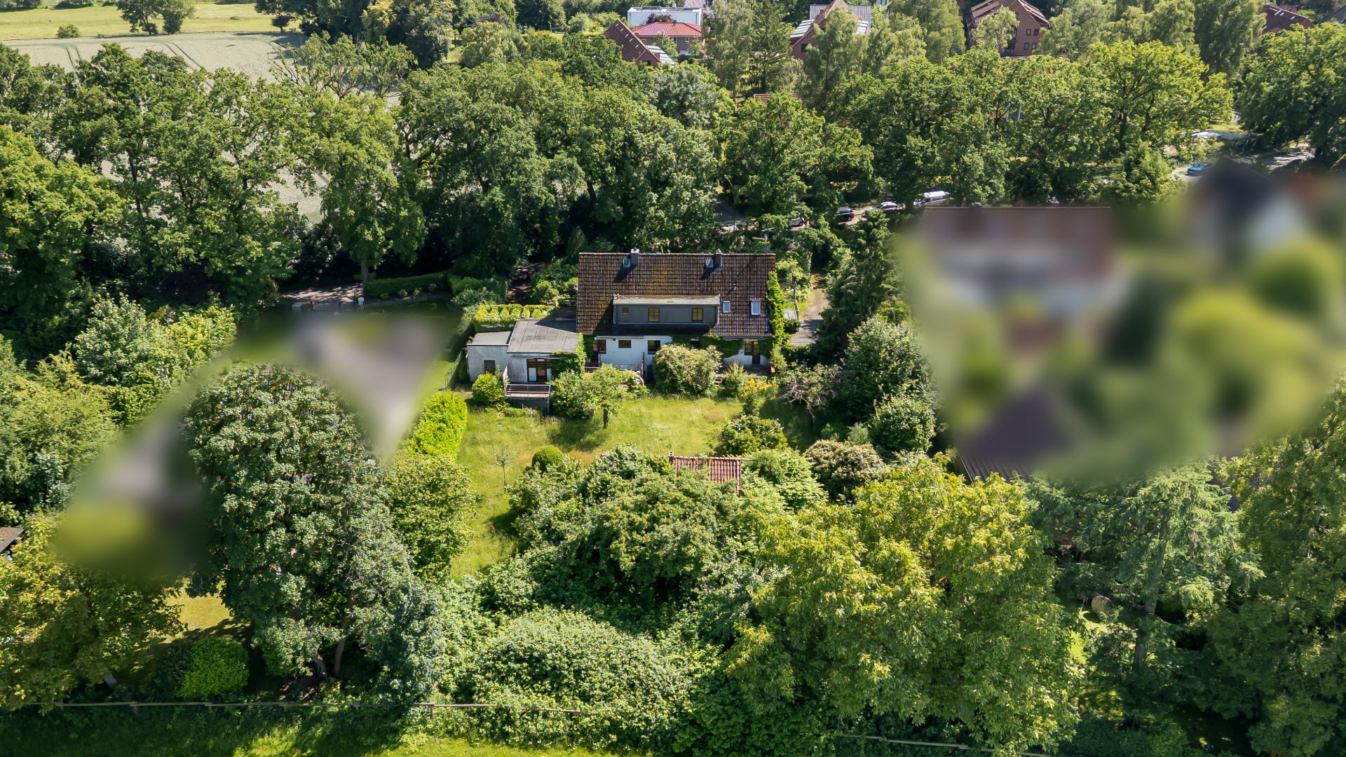 Luftaufnahme eines Hauses mit großem, grünem Garten und vielen Bäumen rundherum.