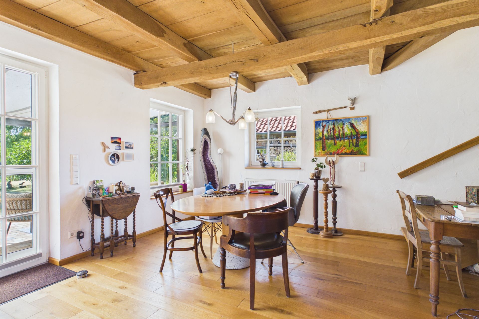 Heller Essbereich mit Holztisch, Stühlen, Fenstern und sichtbaren Holzbalken an der Decke.