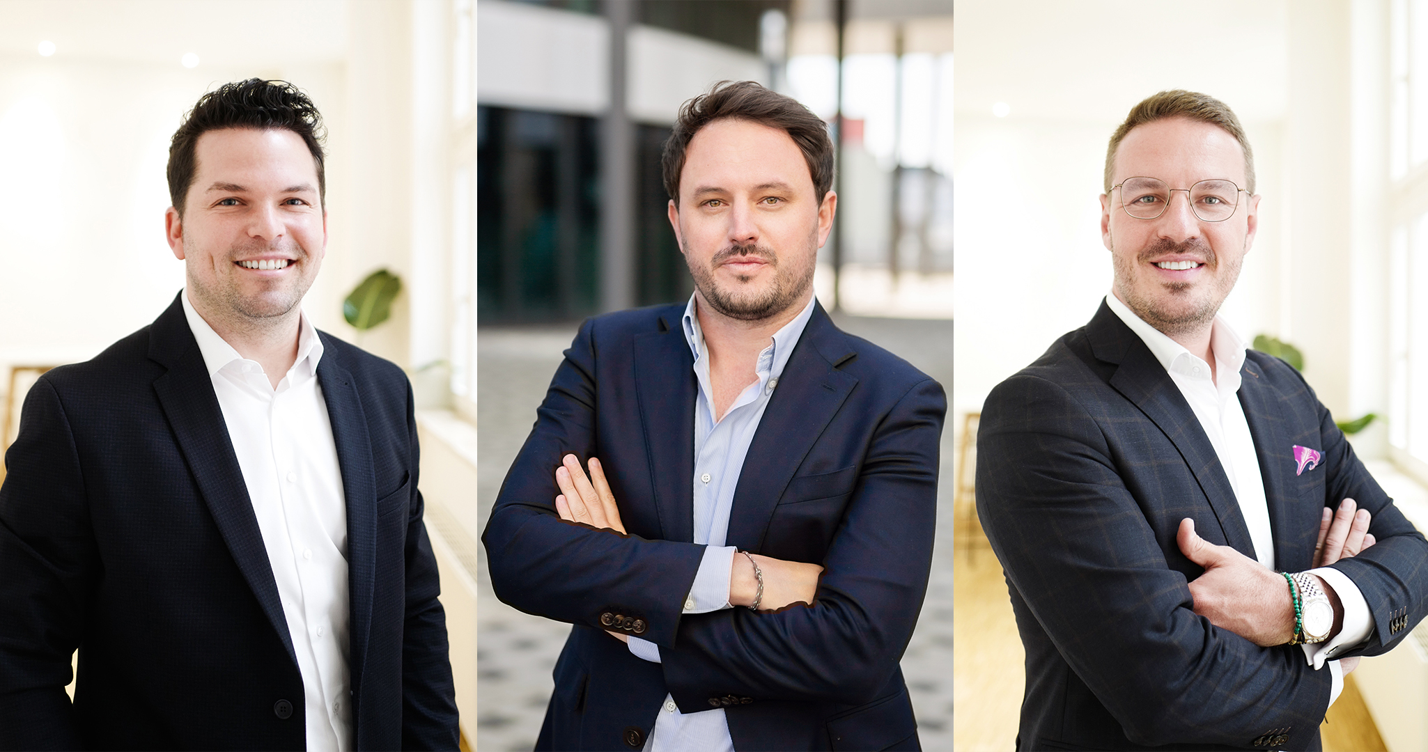 Drei Männer in Anzügen stehen nebeneinander und lächeln in die Kamera.