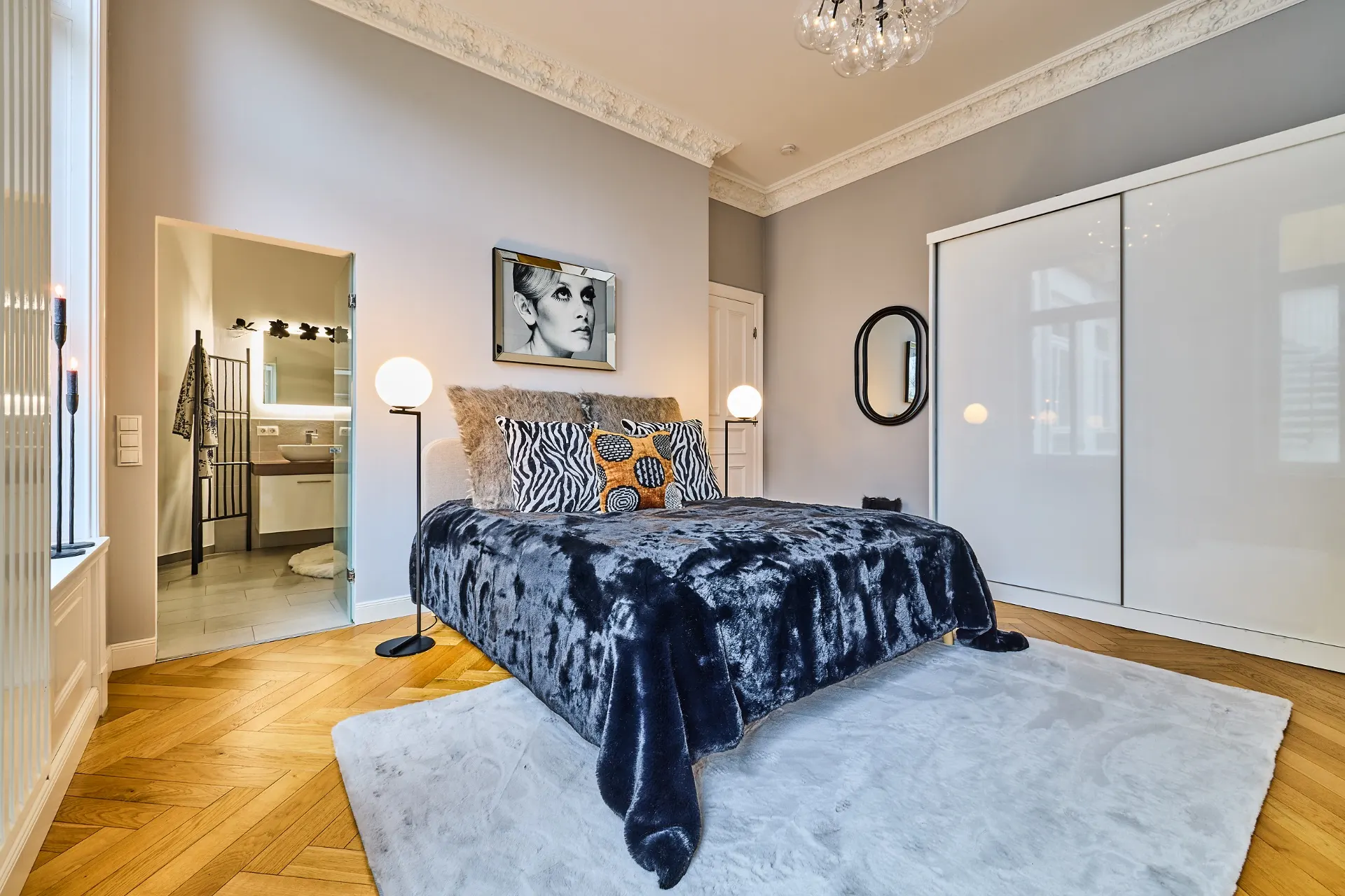 Modernes Schlafzimmer mit Doppelbett, großem Teppich, Kleiderschrank und Zugang zu einem Badezimmer.