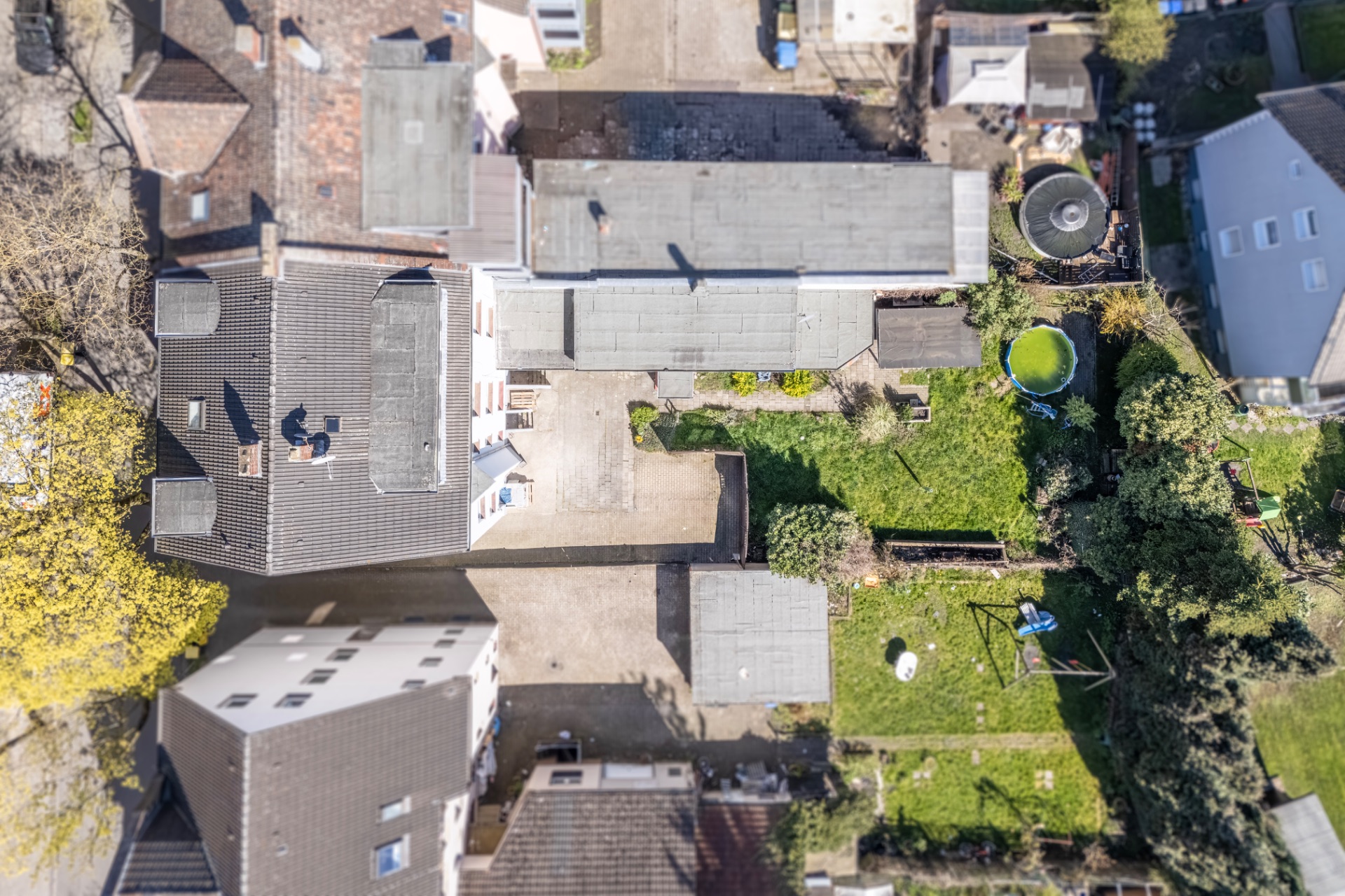 Luftbild eines Wohnhauses mit Garten, Terrasse und angrenzenden Gebäuden.