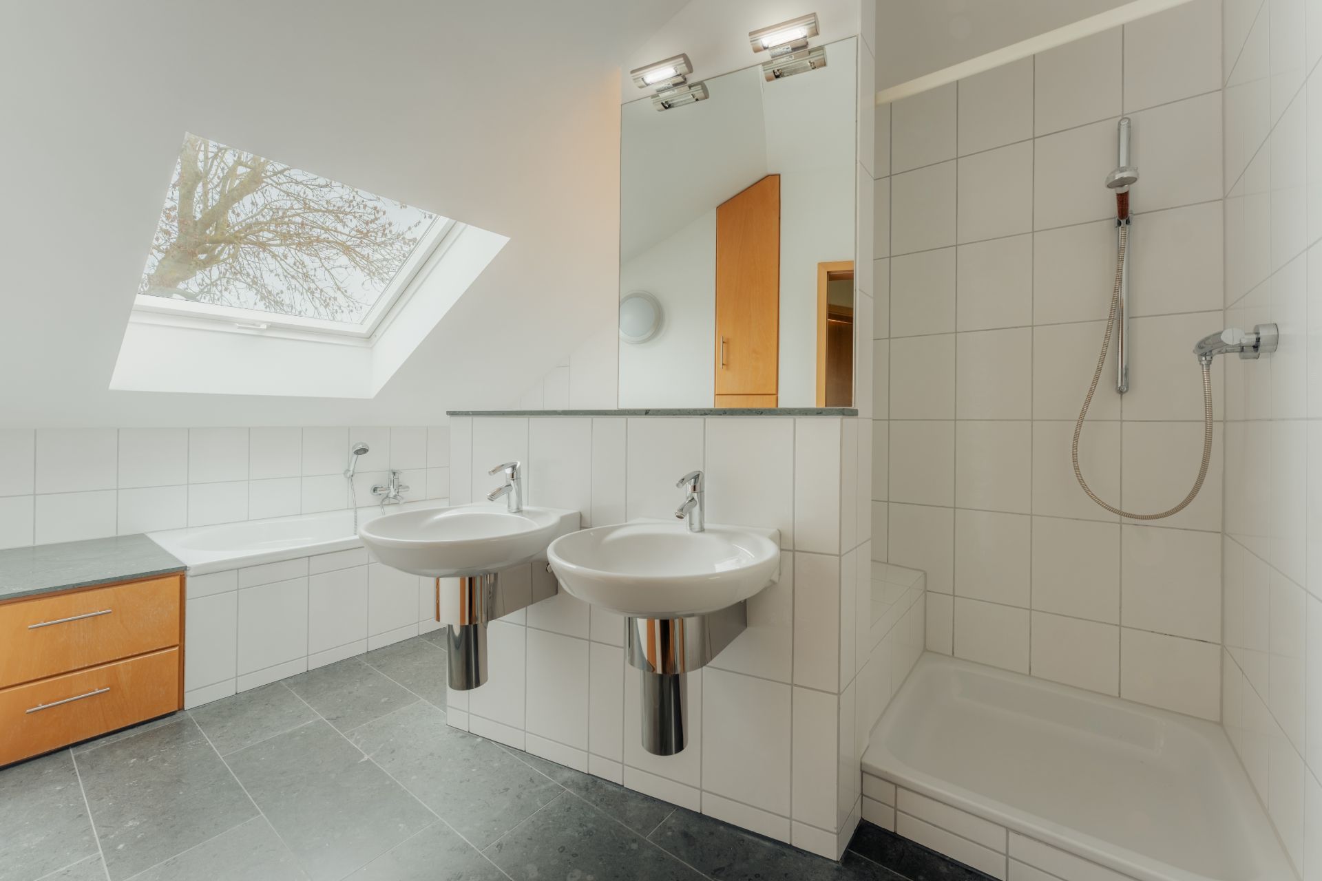 Modernes Badezimmer mit zwei Waschbecken, Dusche, Badewanne und großem Dachfenster.