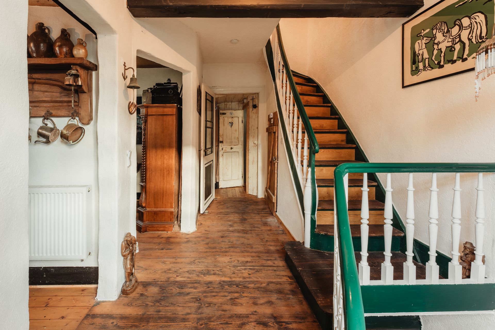 Hausflur mit Holztreppe, Holzboden und Vintage-Dekorationen an den Wänden.