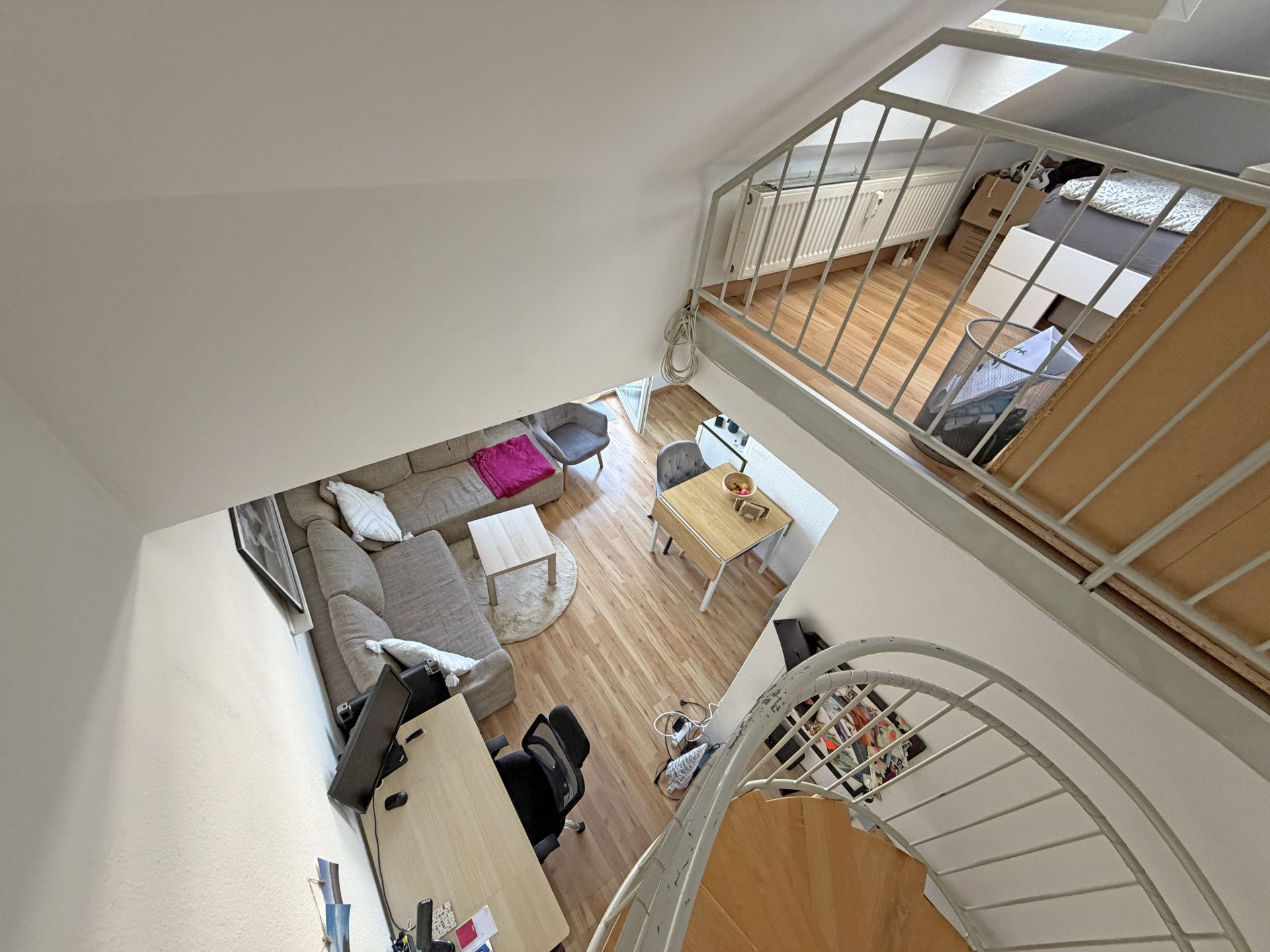 Wohnbereich mit Sofa, Schreibtisch und Esstisch, Blick auf Galerie mit Bett, Wendeltreppe im Vordergrund.