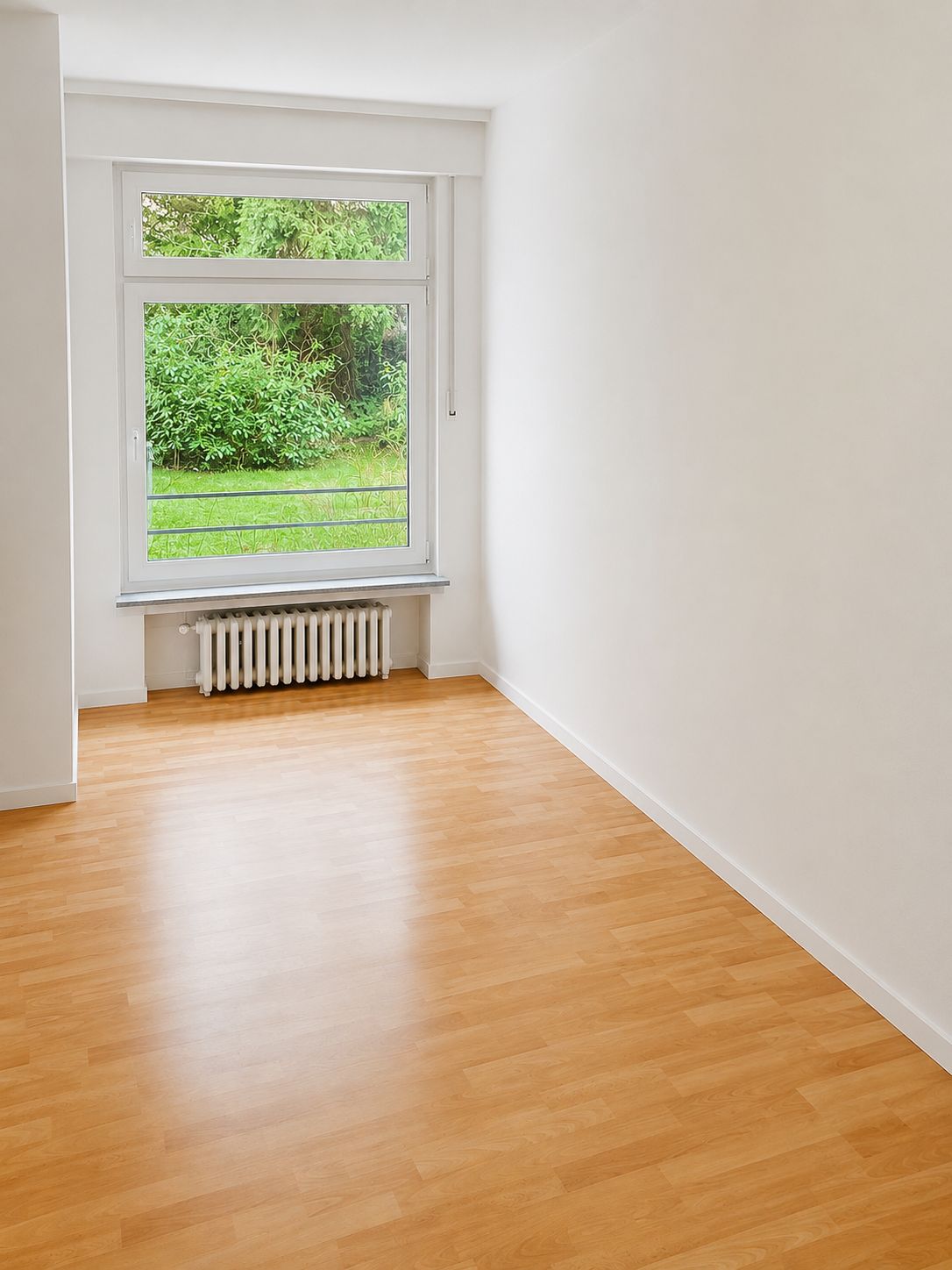 Helles Zimmer mit Laminatboden, großem Fenster und Blick ins Grüne.