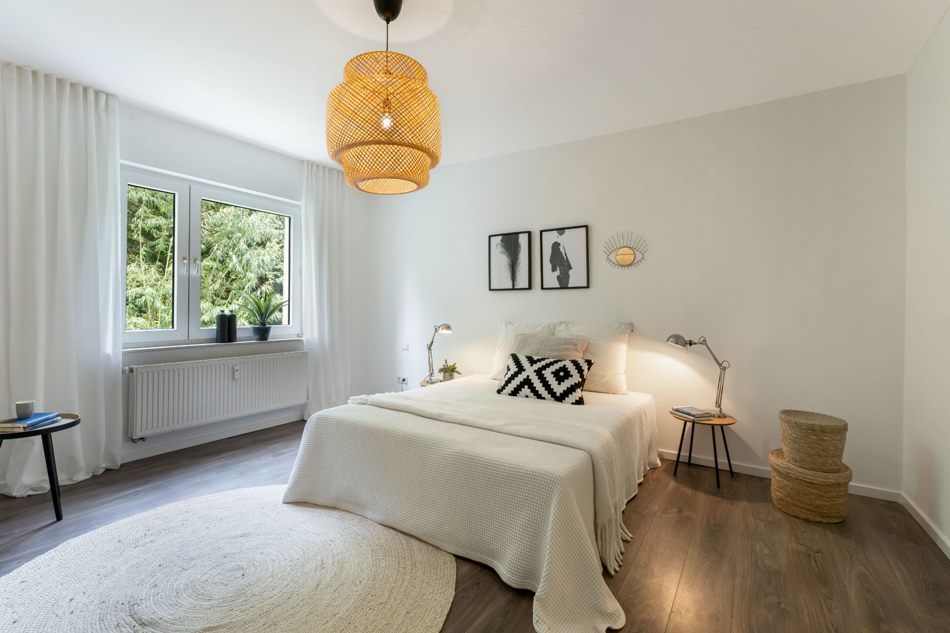 Helles Schlafzimmer mit Doppelbett, Holzboden, großem Fenster und dekorativen Lampen.