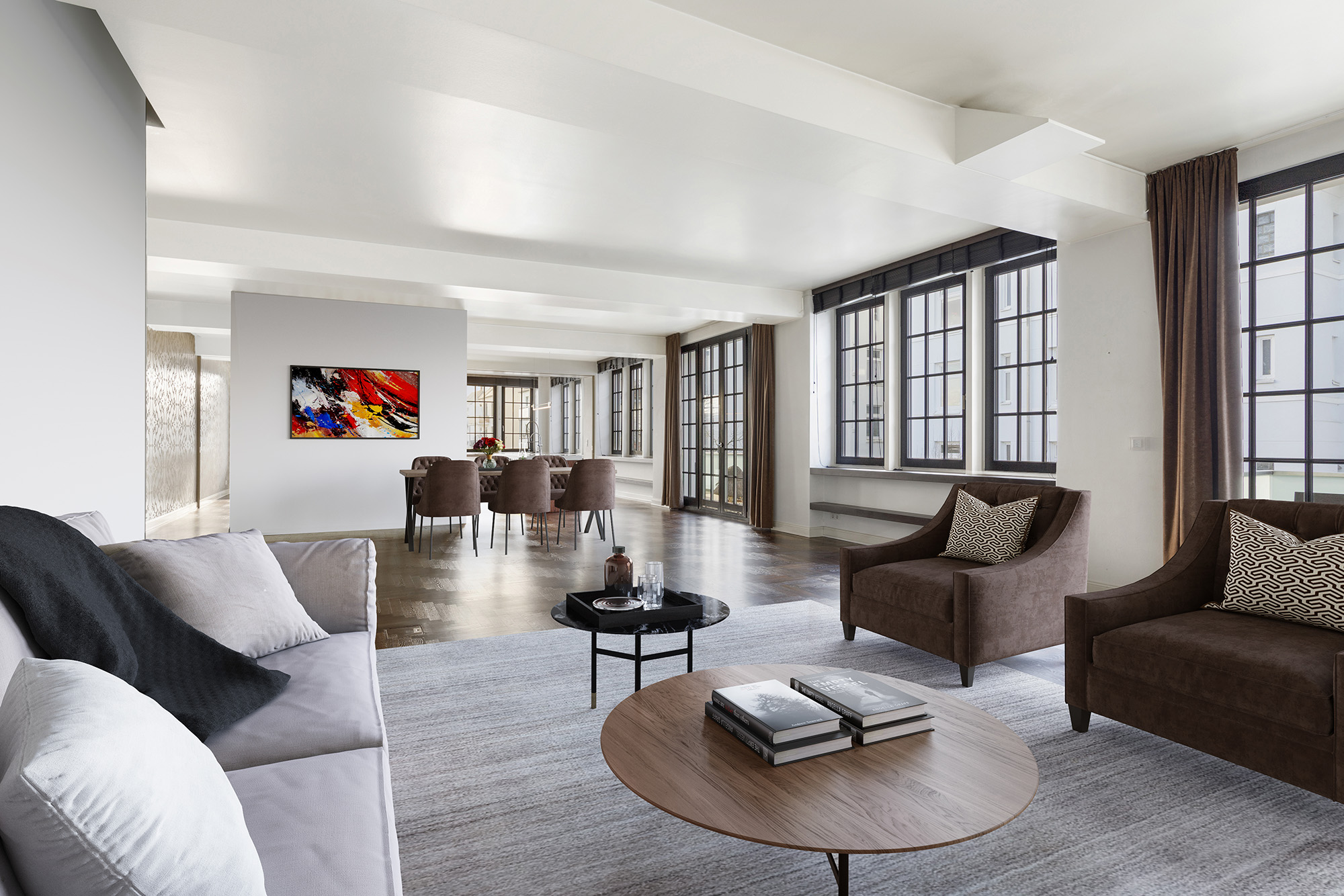 Modernes Wohnzimmer mit Sofa, zwei Sesseln, Couchtisch und großem Essbereich im Hintergrund.