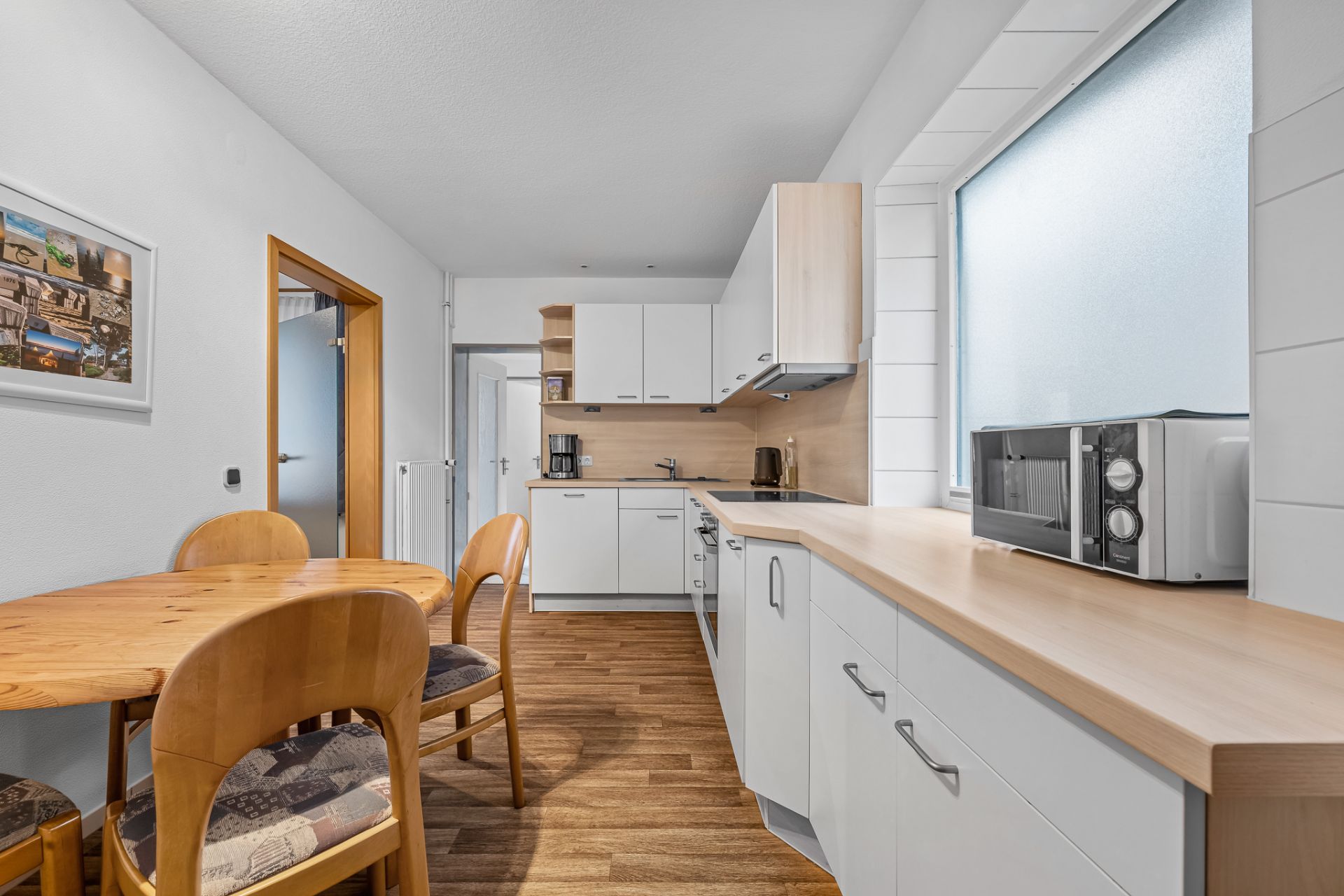 Moderne Einbauküche mit Holzarbeitsplatte und Essbereich mit vier Stühlen.
