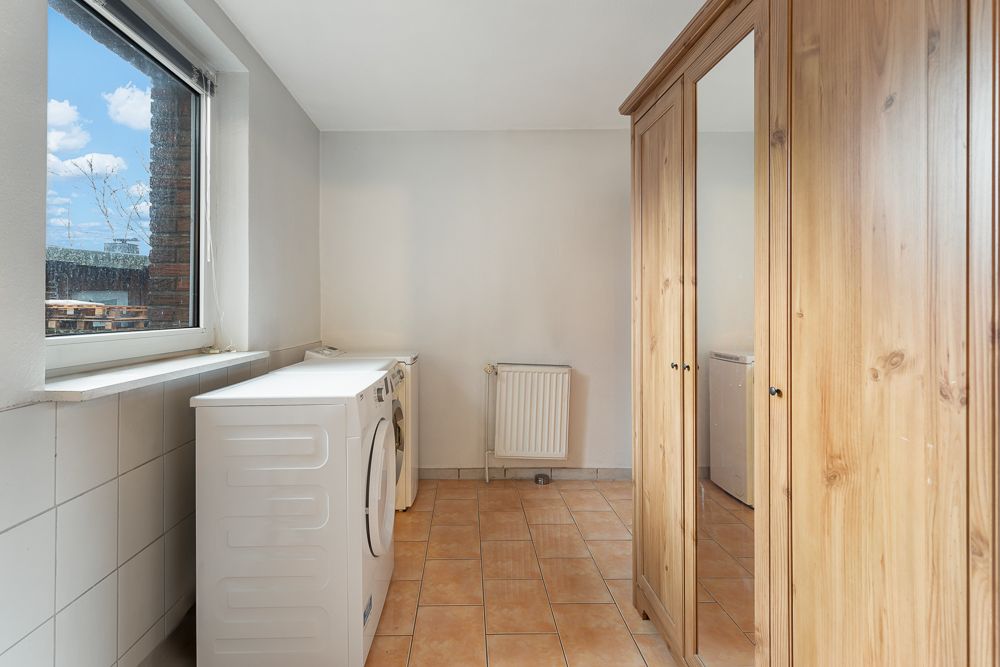 Hauswirtschaftsraum mit Waschmaschine, Trockner und großem Holzkleiderschrank.