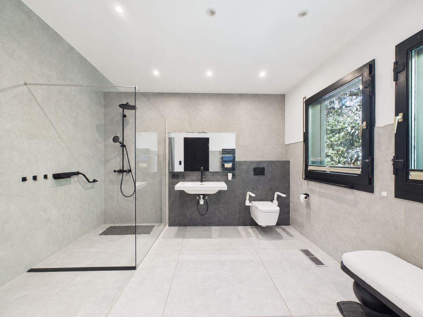 Modernes barrierefreies Badezimmer mit ebenerdiger Dusche, Waschbecken und WC.