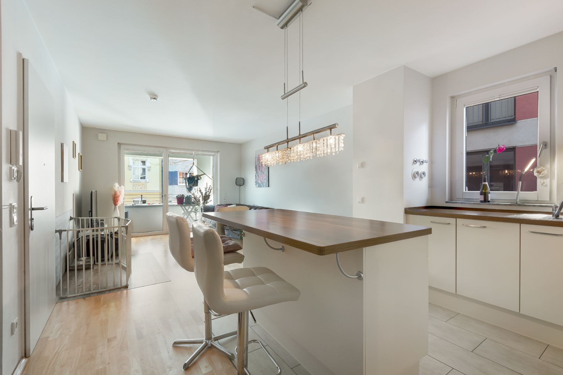 Moderne Wohnküche mit Tresen, zwei Barhockern und Zugang zum Balkon.