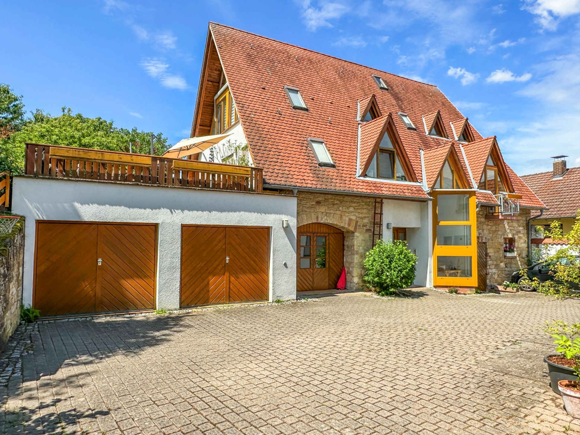 Großes Wohnhaus mit rotem Satteldach, Doppelgarage und gepflastertem Hof.