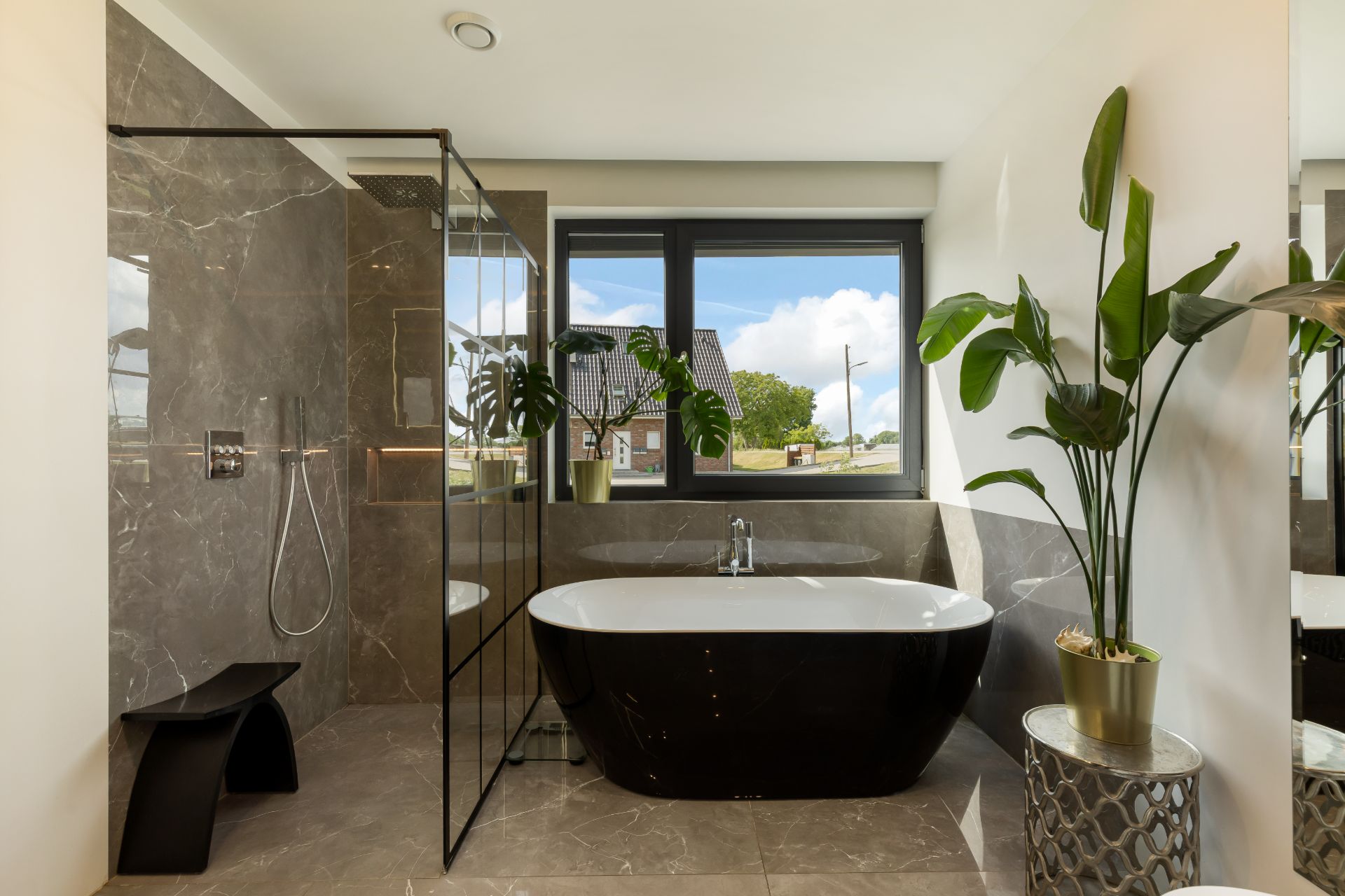 Modernes Badezimmer mit freistehender Badewanne, Dusche, großen Fenstern und Zimmerpflanzen.