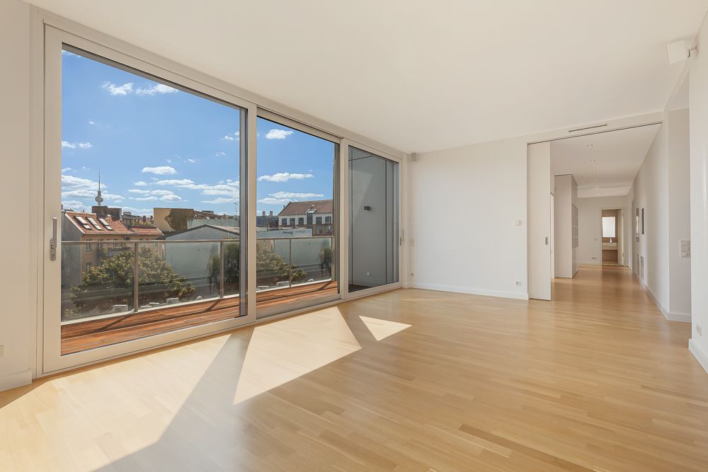 Helles Wohnzimmer mit großen Glasfronten und Zugang zu einem Balkon, Blick auf die Stadt.