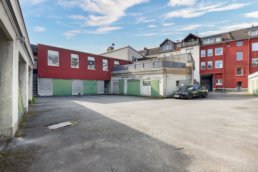 Innenhof mit mehreren Garagentoren und geparktem Auto vor Wohnhäusern.