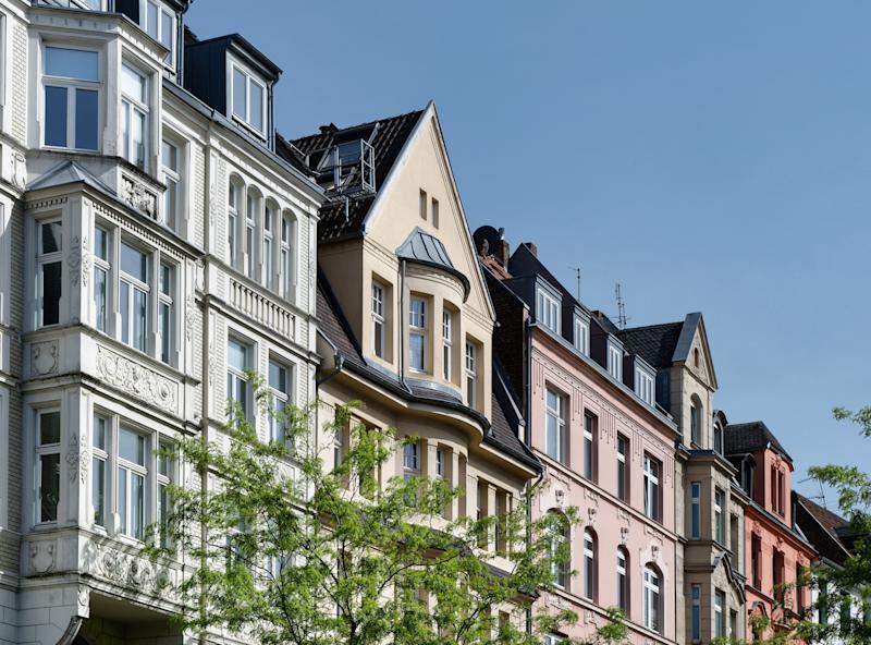 Mehrstöckige Wohnhäuser an einer Straßenecke mit U-Bahn-Eingang und Ampel.