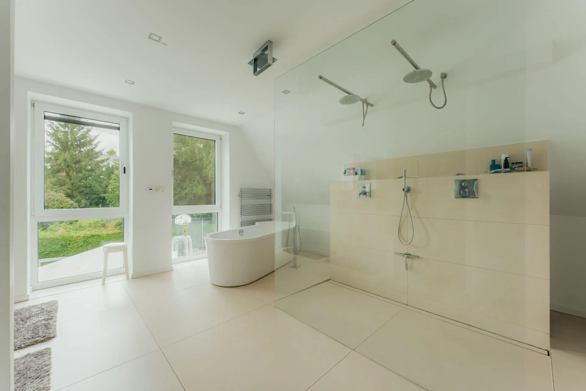 Modernes Badezimmer mit freistehender Badewanne und großer, offener Dusche mit zwei Duschköpfen.