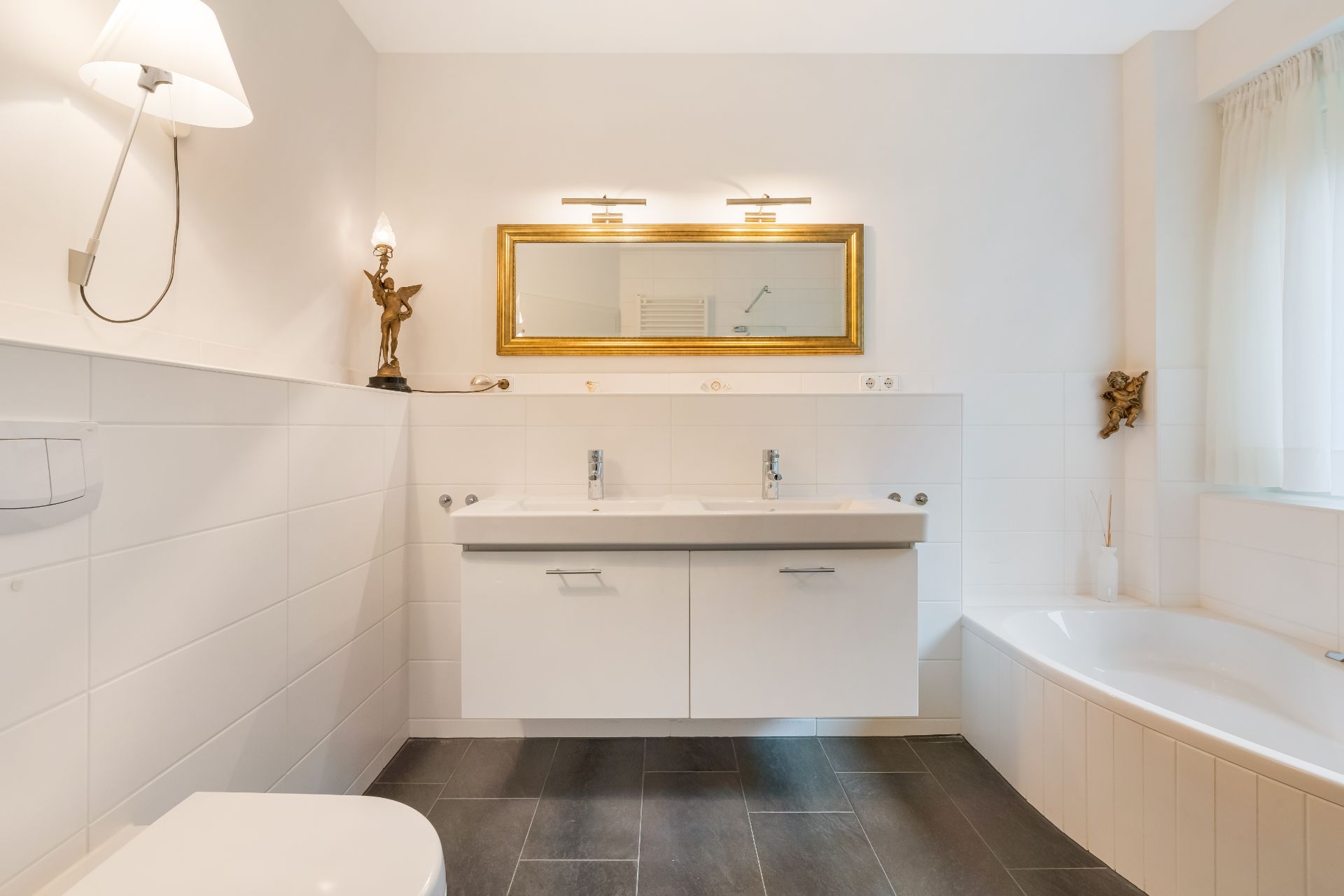 Modernes Badezimmer mit Doppelwaschbecken, Badewanne, Spiegel und weißen Fliesen.