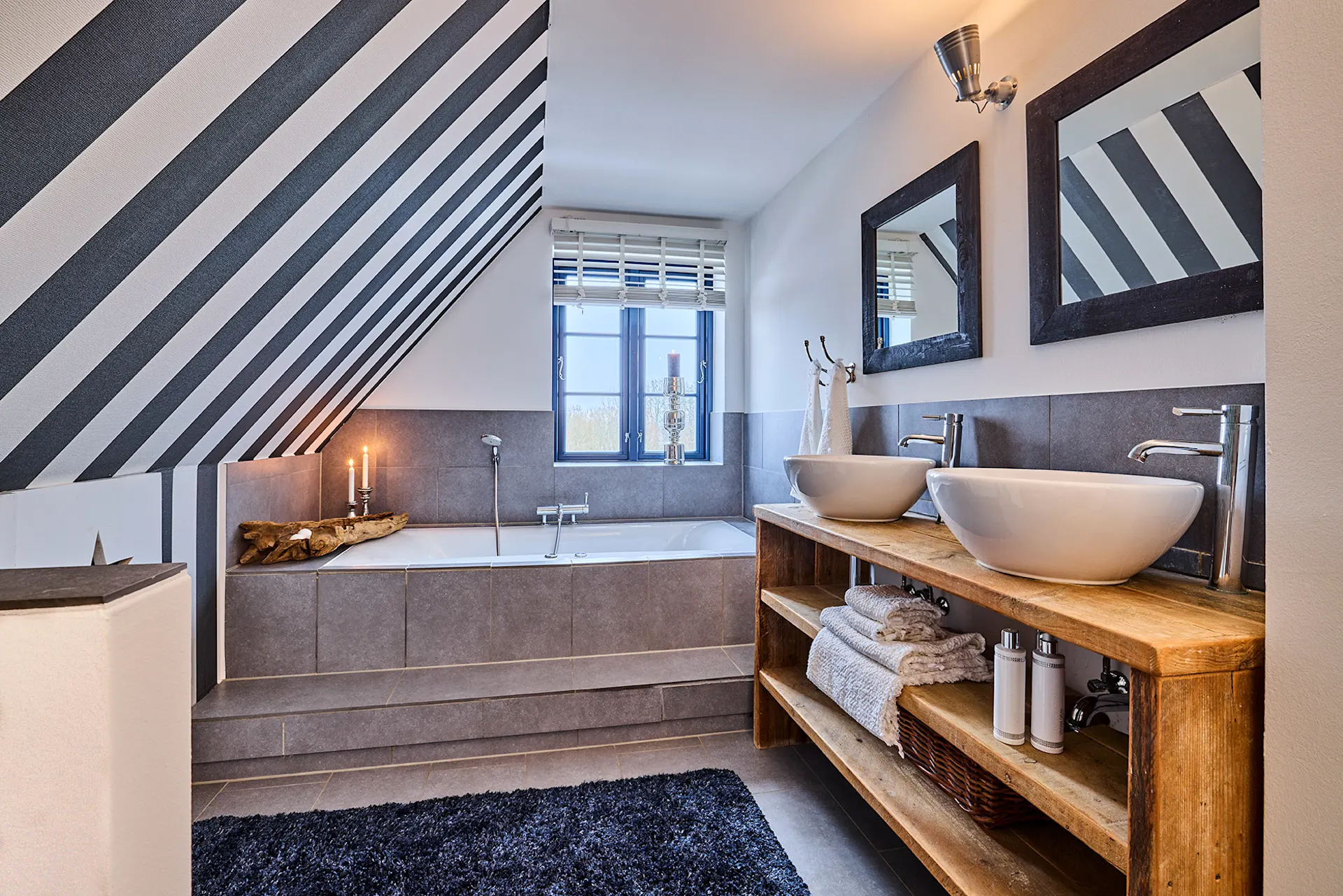 Modernes Badezimmer mit Doppelwaschbecken, Badewanne und schräger Decke mit Streifenmuster.