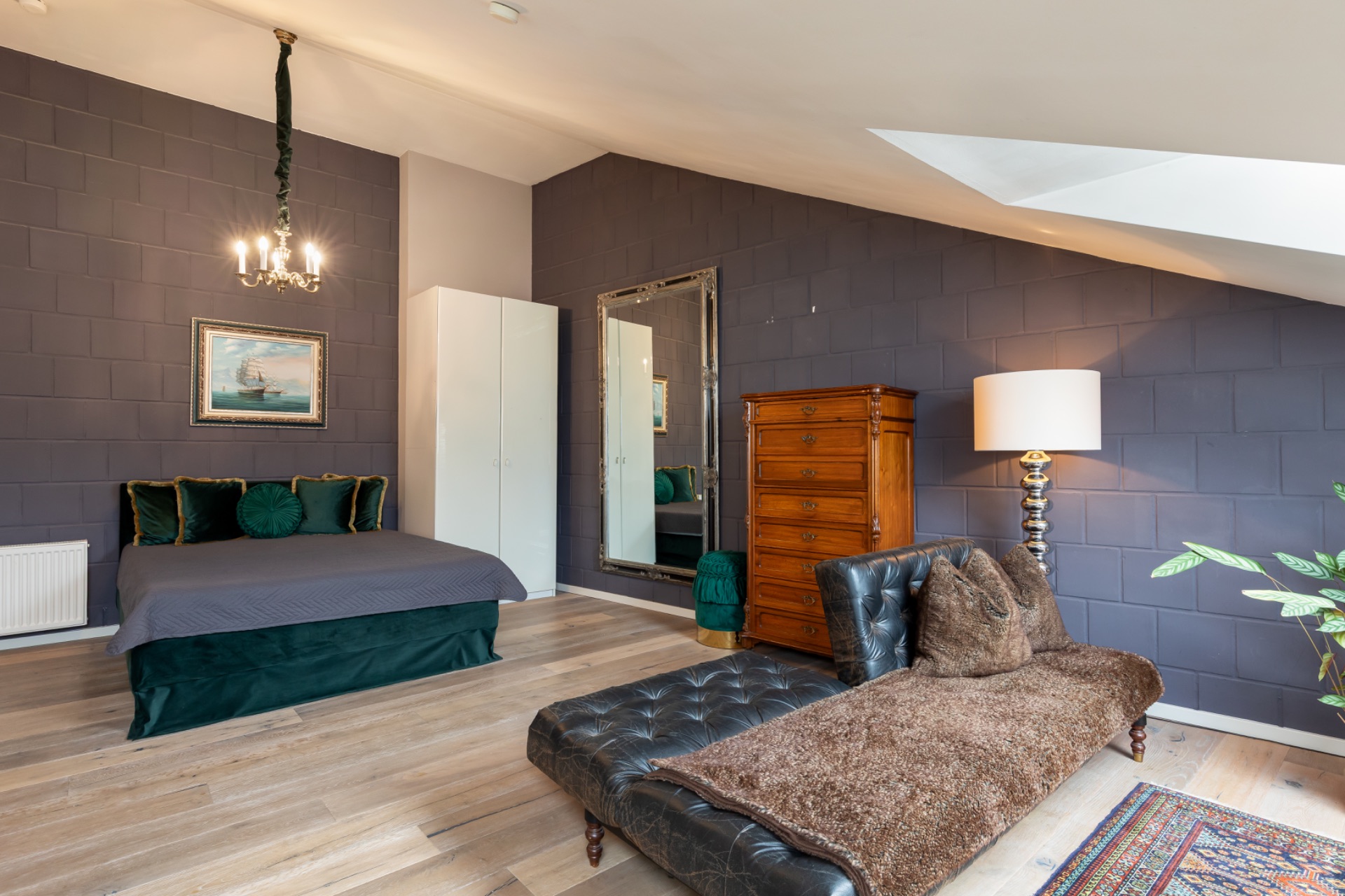 Großes Schlafzimmer mit Doppelbett, Spiegel, Kommode, Sitzbank, Lampe und Pflanzen.