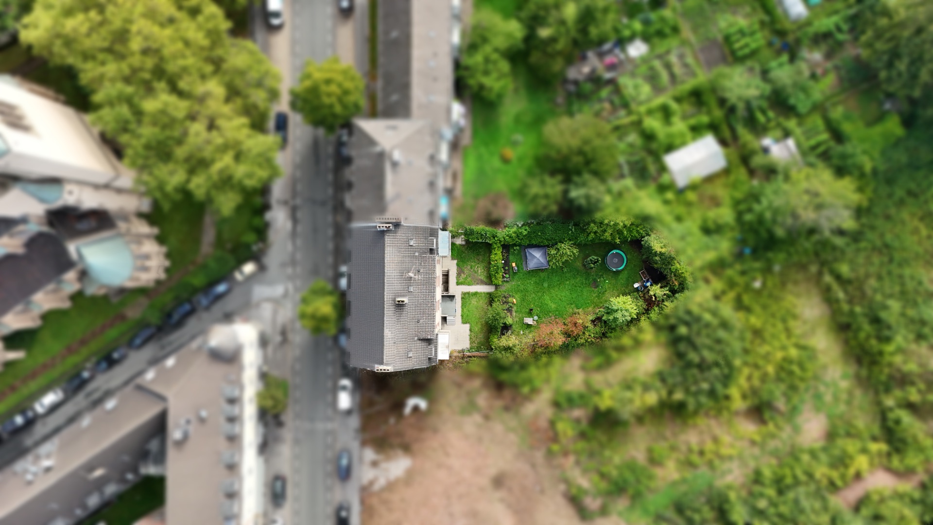 Luftaufnahme eines Wohnhauses mit langem, grünen Garten und Gartenmöbeln.