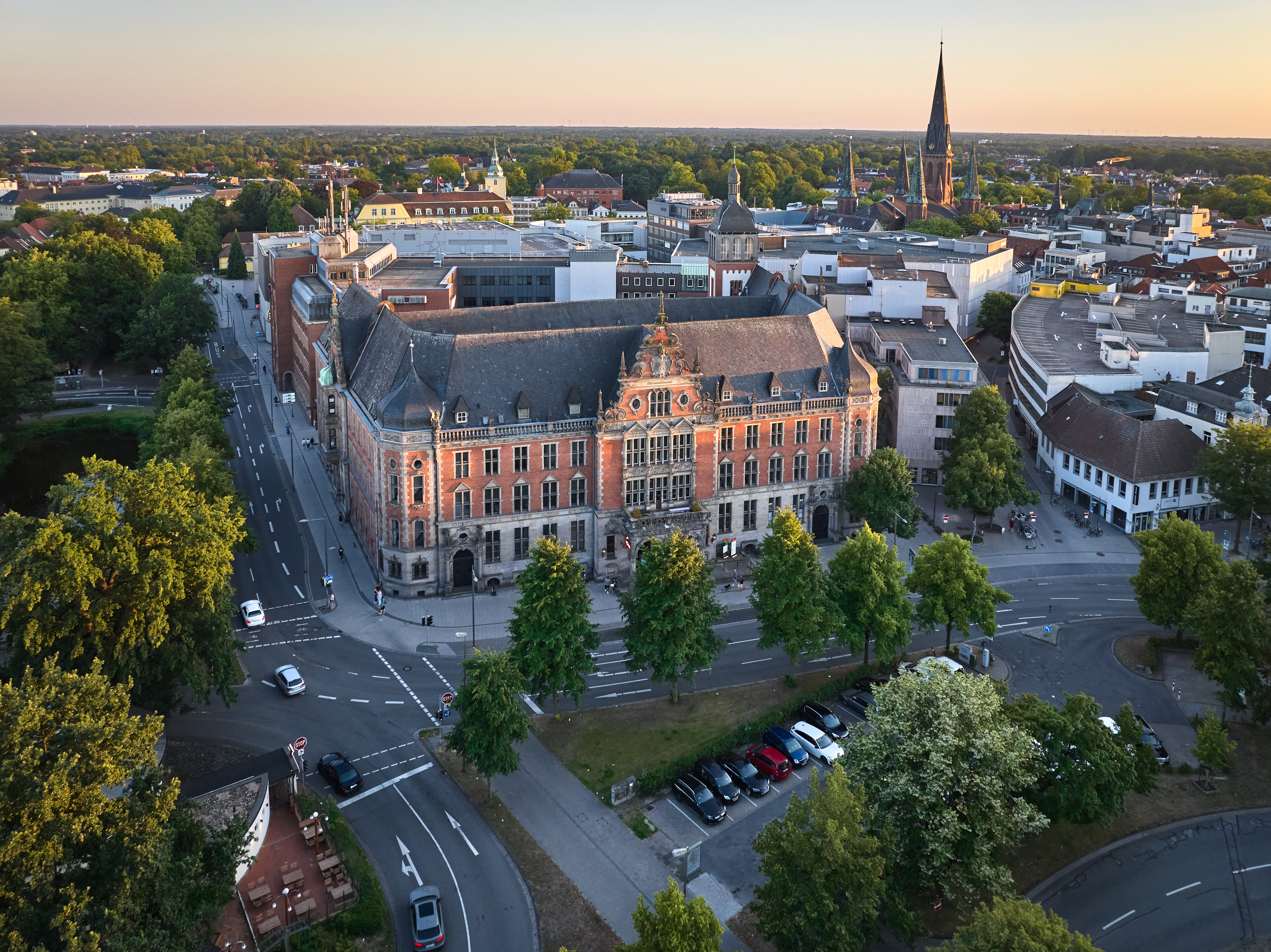 Luftaufnahme eines großen, historischen Gebäudes mit Bäumen und Straßen rundherum.