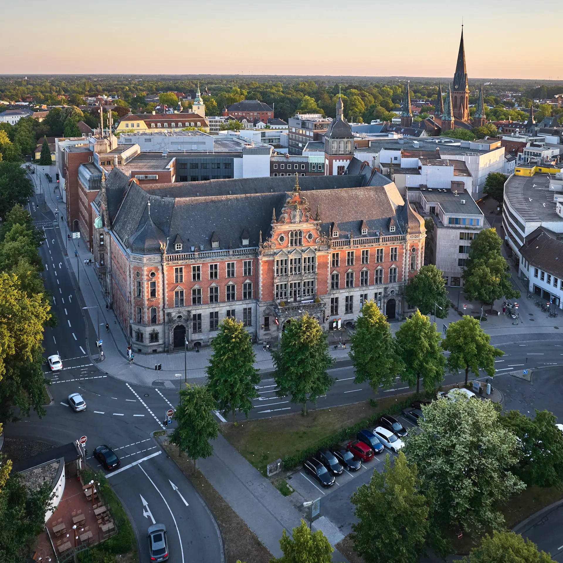 Luftaufnahme eines großen, historischen Gebäudes mit Bäumen und Straßen rundherum.