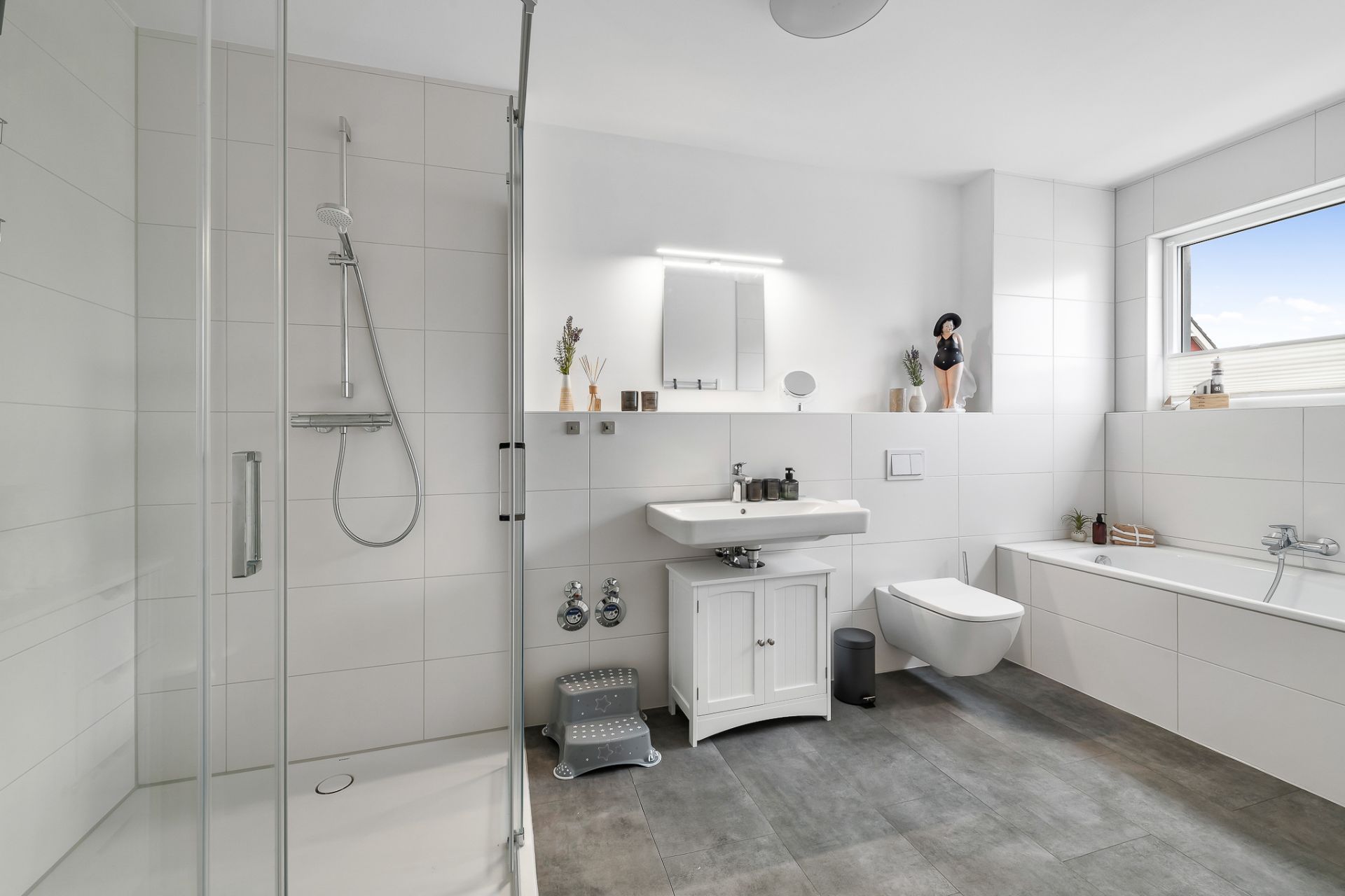 Modernes Badezimmer mit Dusche, Badewanne, Waschbecken, WC und Fenster.