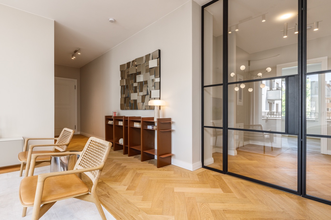 Heller Raum mit zwei Holzstühlen, Regal, Lampe und großer Glaswand.