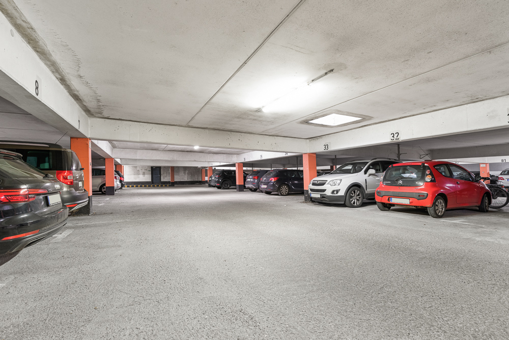 Tiefgarage mit mehreren geparkten Autos und orangefarbenen Säulen.