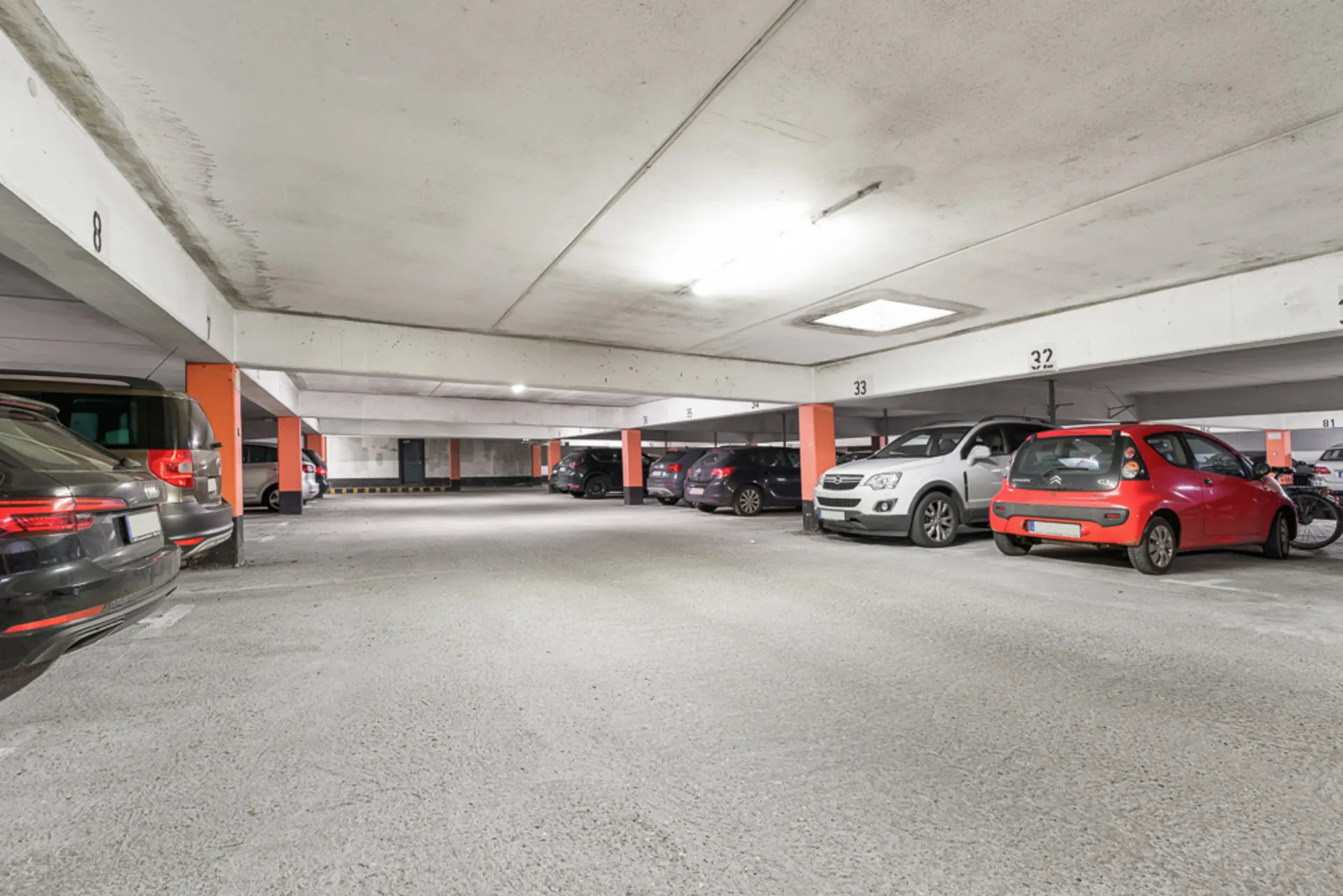 Tiefgarage mit mehreren geparkten Autos und orangefarbenen Säulen.