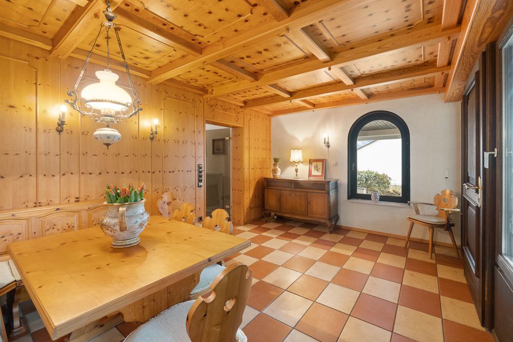 Heller Essbereich mit Holzmöbeln, kariertem Fliesenboden und rustikaler Decke.