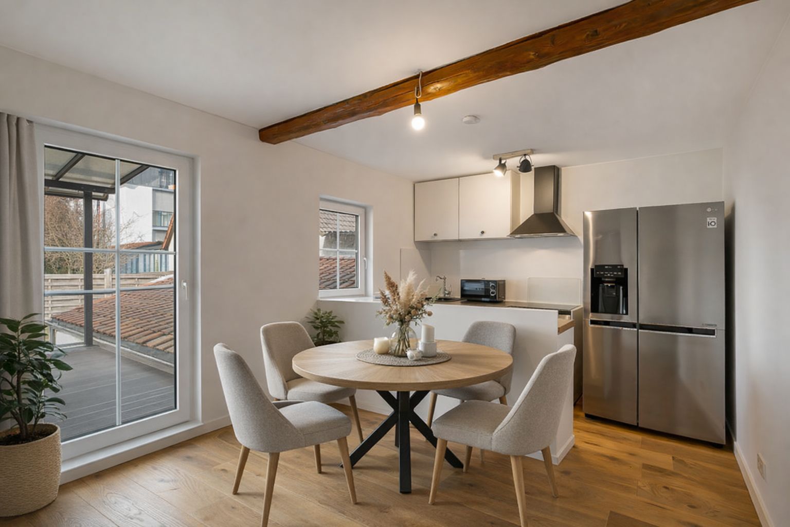 Moderner Essbereich mit rundem Holztisch, vier Stühlen und offener Küche mit großem Kühlschrank.