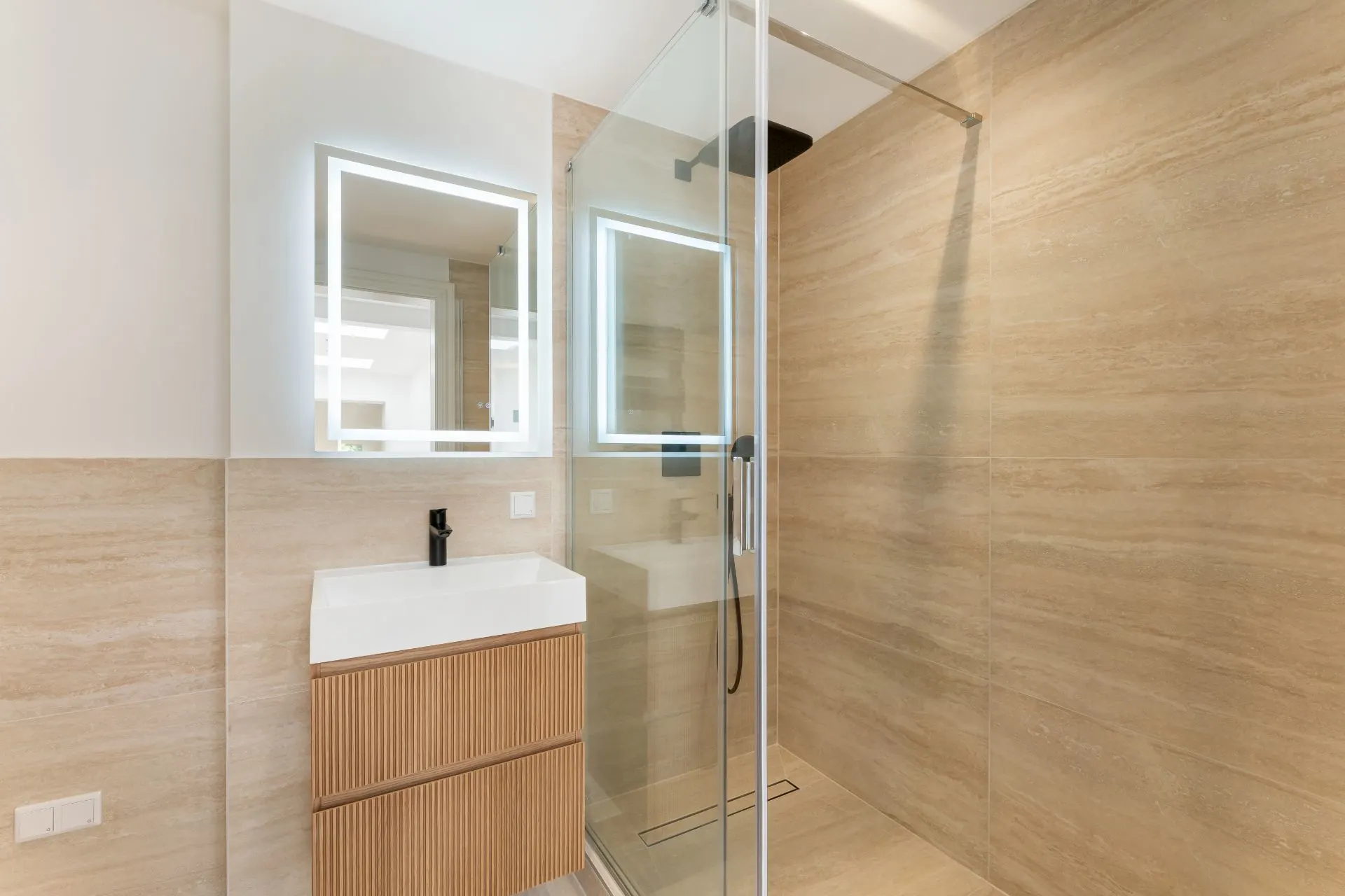 Modernes Badezimmer mit Holzwaschtisch, Spiegel und begehbarer Glasdusche.